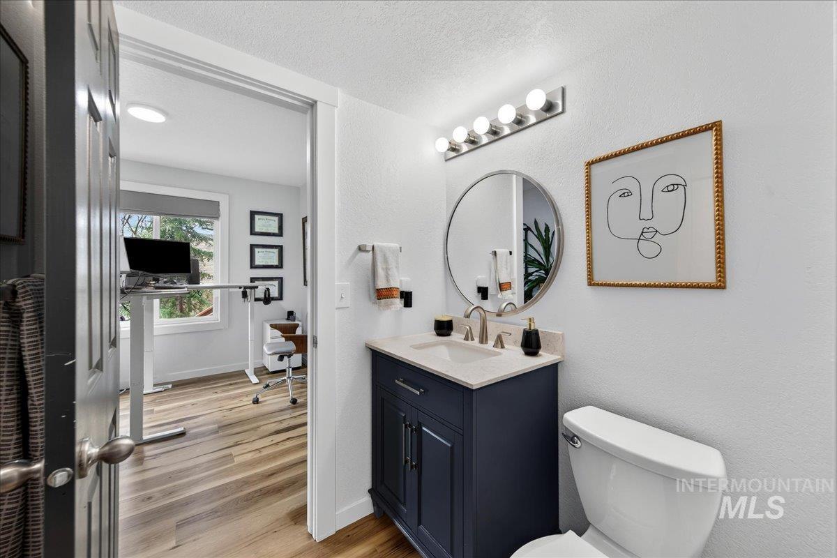 Bathroom featuring vanity, light wood-style floors, a textured wall, and a textured ceiling