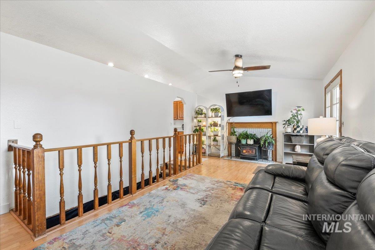 Living room with wood finished floors, a ceiling fan, lofted ceiling, and arched walkways