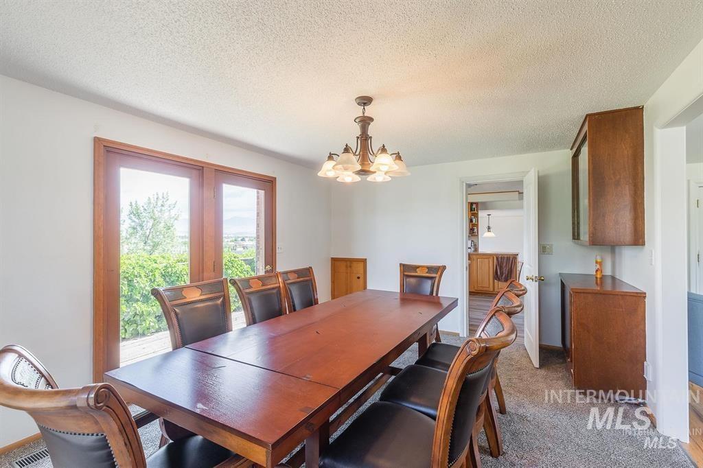 Dining area with a chandelier, light carpet, a textured ceiling, and french doors
