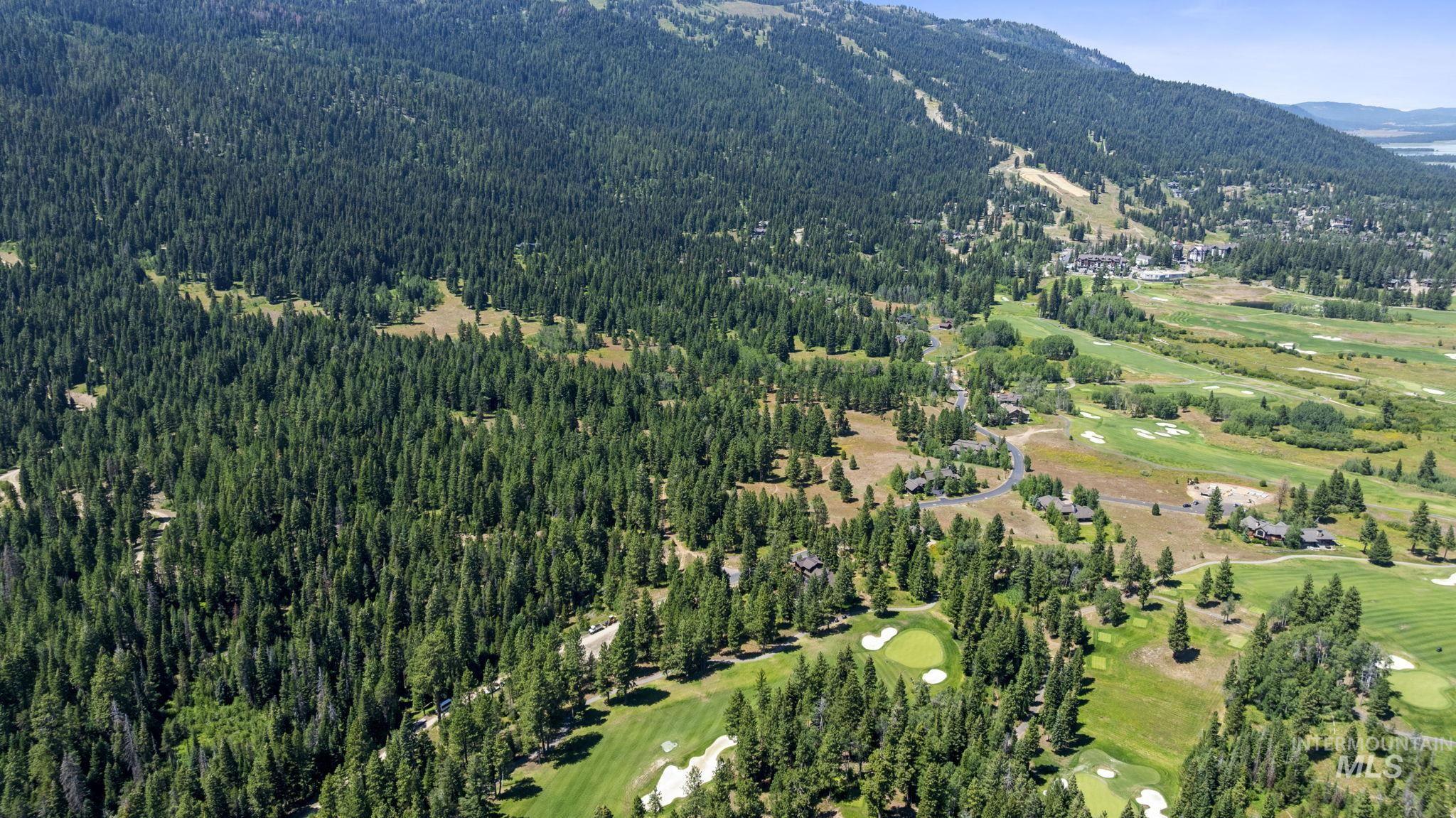 Aerial view of property and surrounding area featuring a mountain backdrop and a golf course