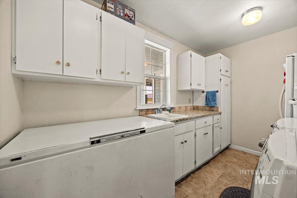 Kitchen featuring white cabinets, light countertops, and freestanding refrigerator
