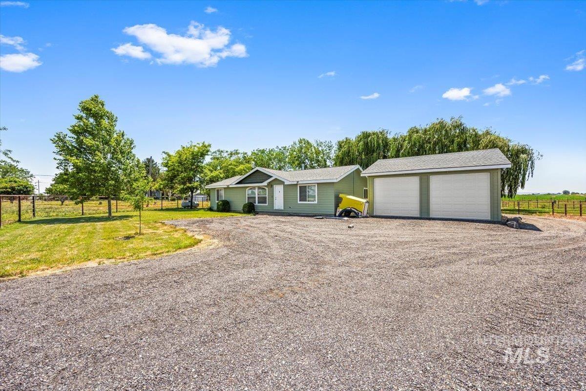 Ranch-style home featuring gravel driveway and a garage