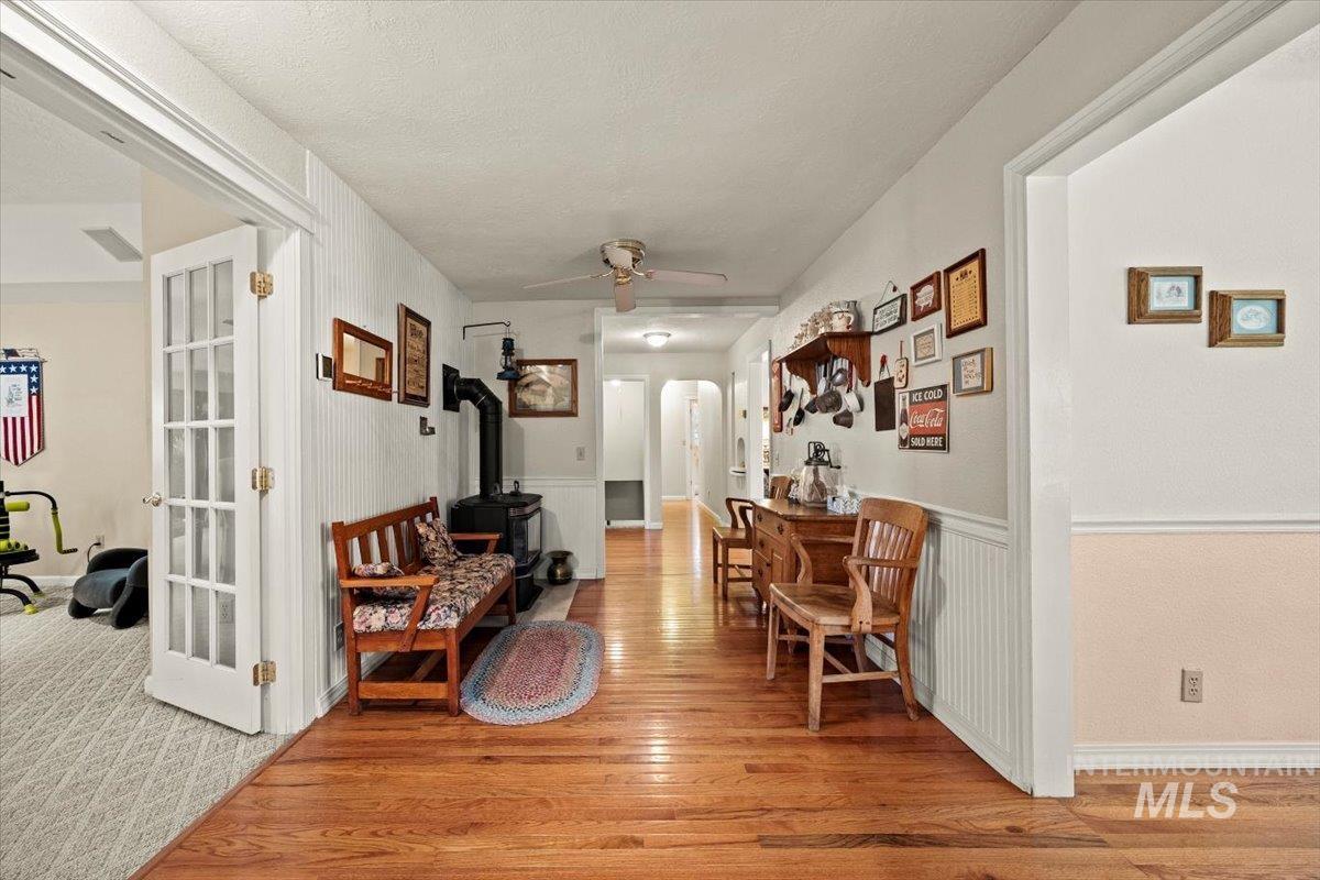 Hall with arched walkways, light wood-style floors, and wainscoting