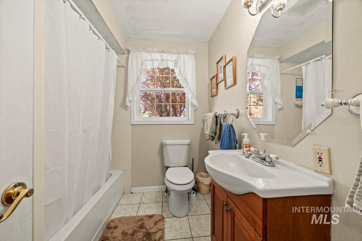 Bathroom with vanity, shower / bath combo with shower curtain, and tile patterned floors