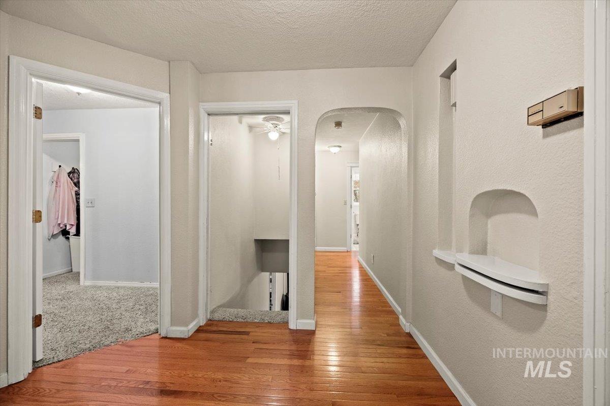 Hallway featuring hardwood / wood-style floors, arched walkways, and a textured ceiling
