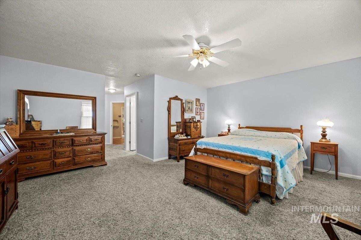 Bedroom with light carpet, ceiling fan, and a textured ceiling