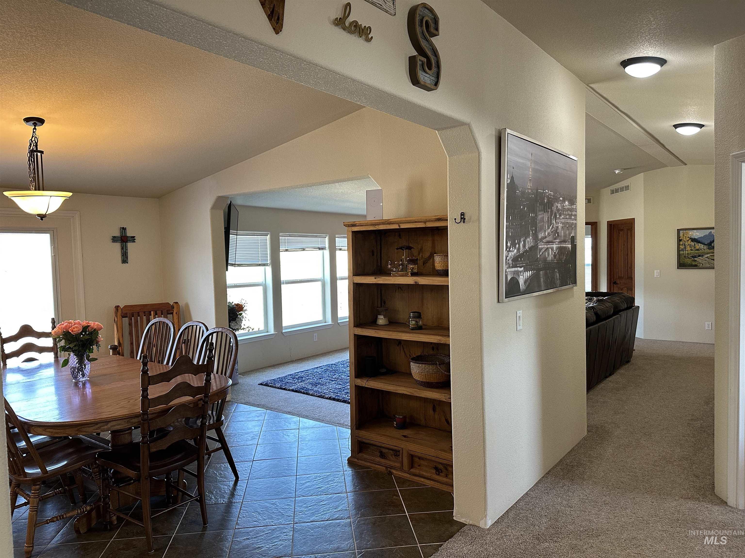 Carpeted dining room featuring vaulted ceiling and a textured ceiling