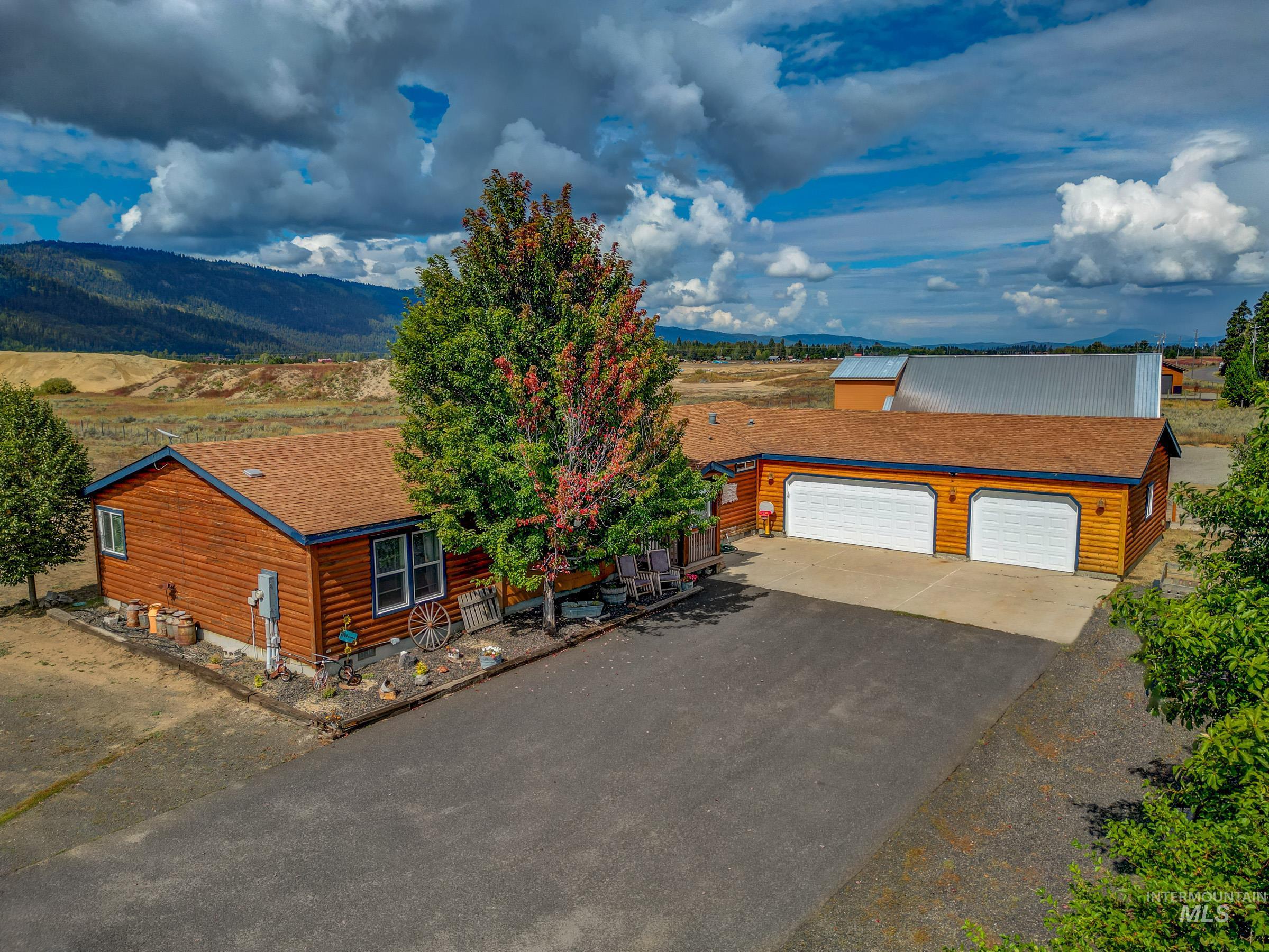 View of front facade with a garage, a shingled roof, asphalt driveway, an outbuilding, and a mountain view