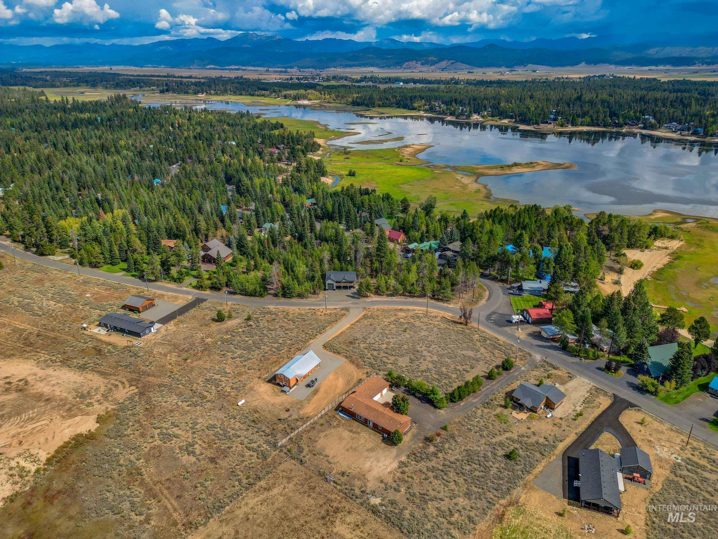 Aerial view of property and surrounding area featuring a water and mountain view and a forest