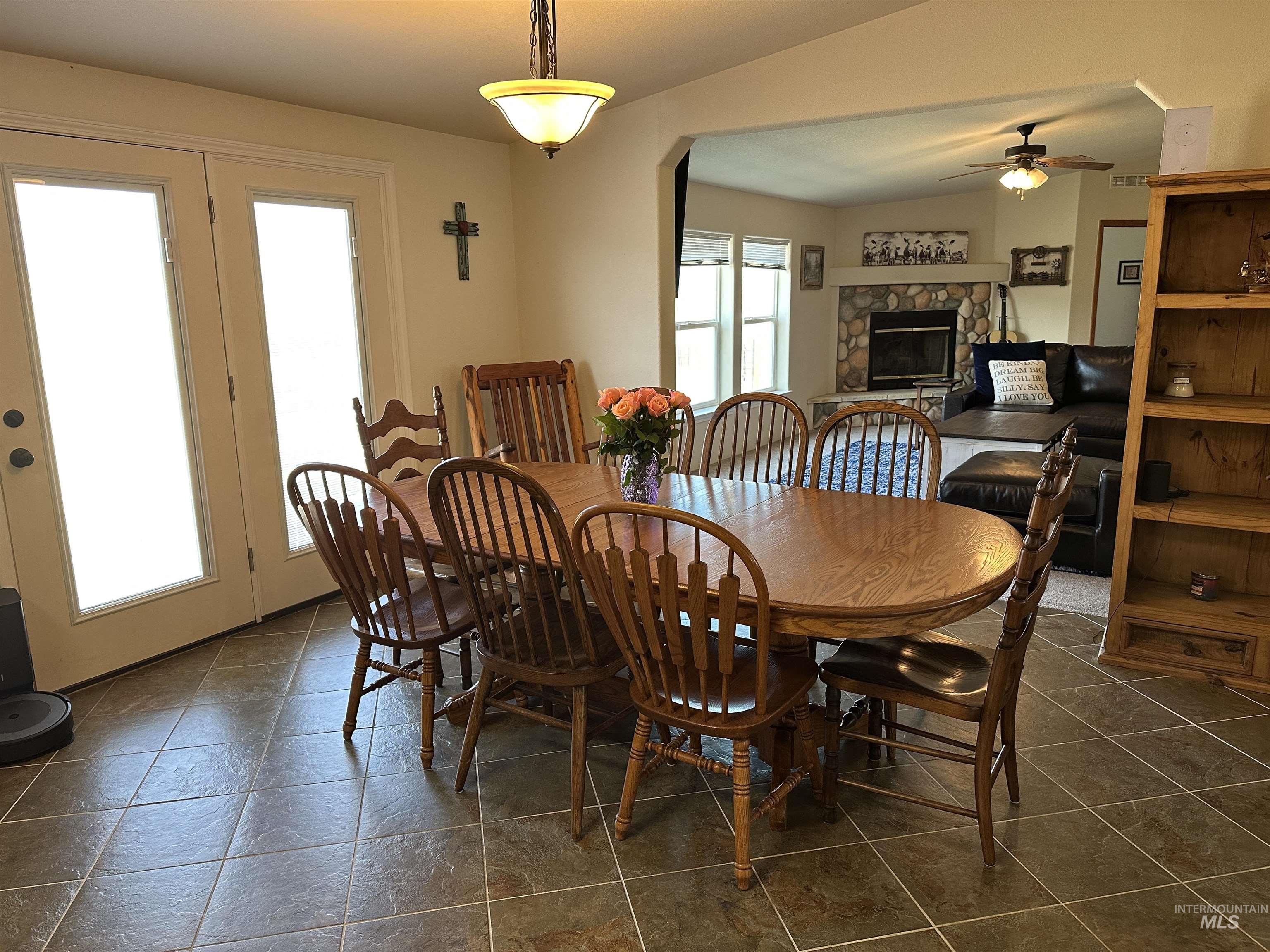 Dining area featuring a fireplace, vaulted ceiling, and a ceiling fan
