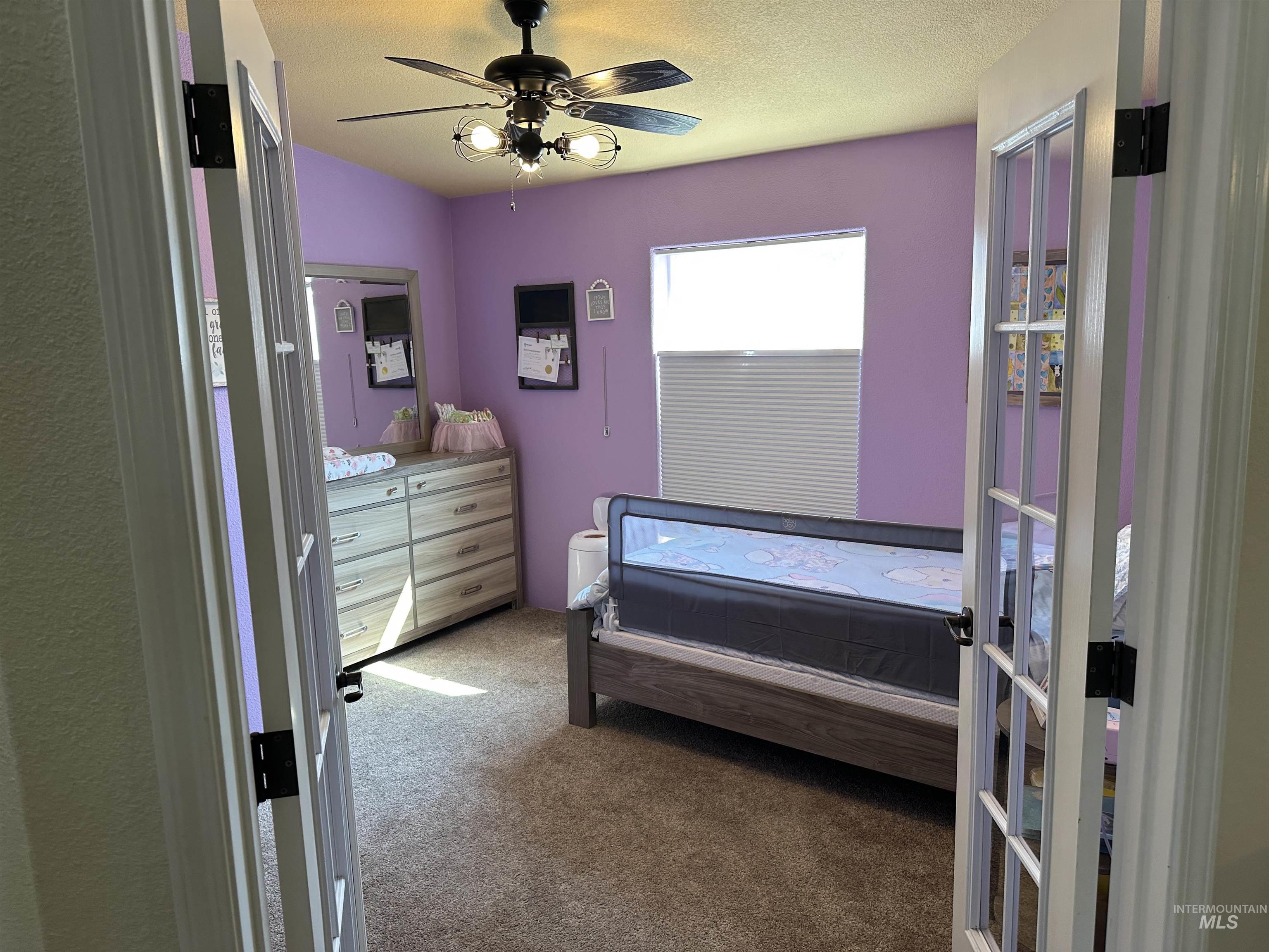 Carpeted bedroom featuring ceiling fan and a textured ceiling