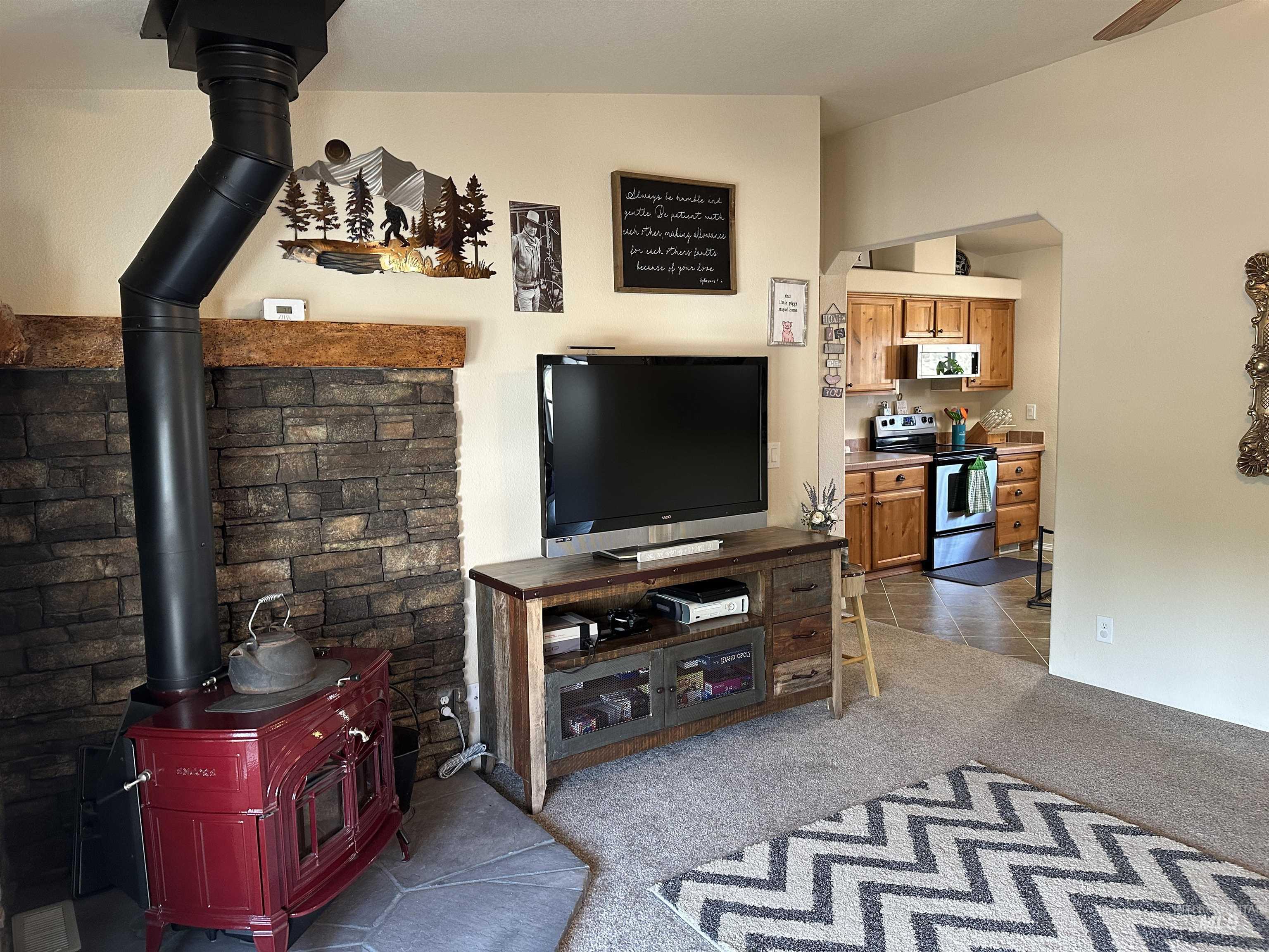 Living room featuring a wood stove, light colored carpet, and light tile patterned floors