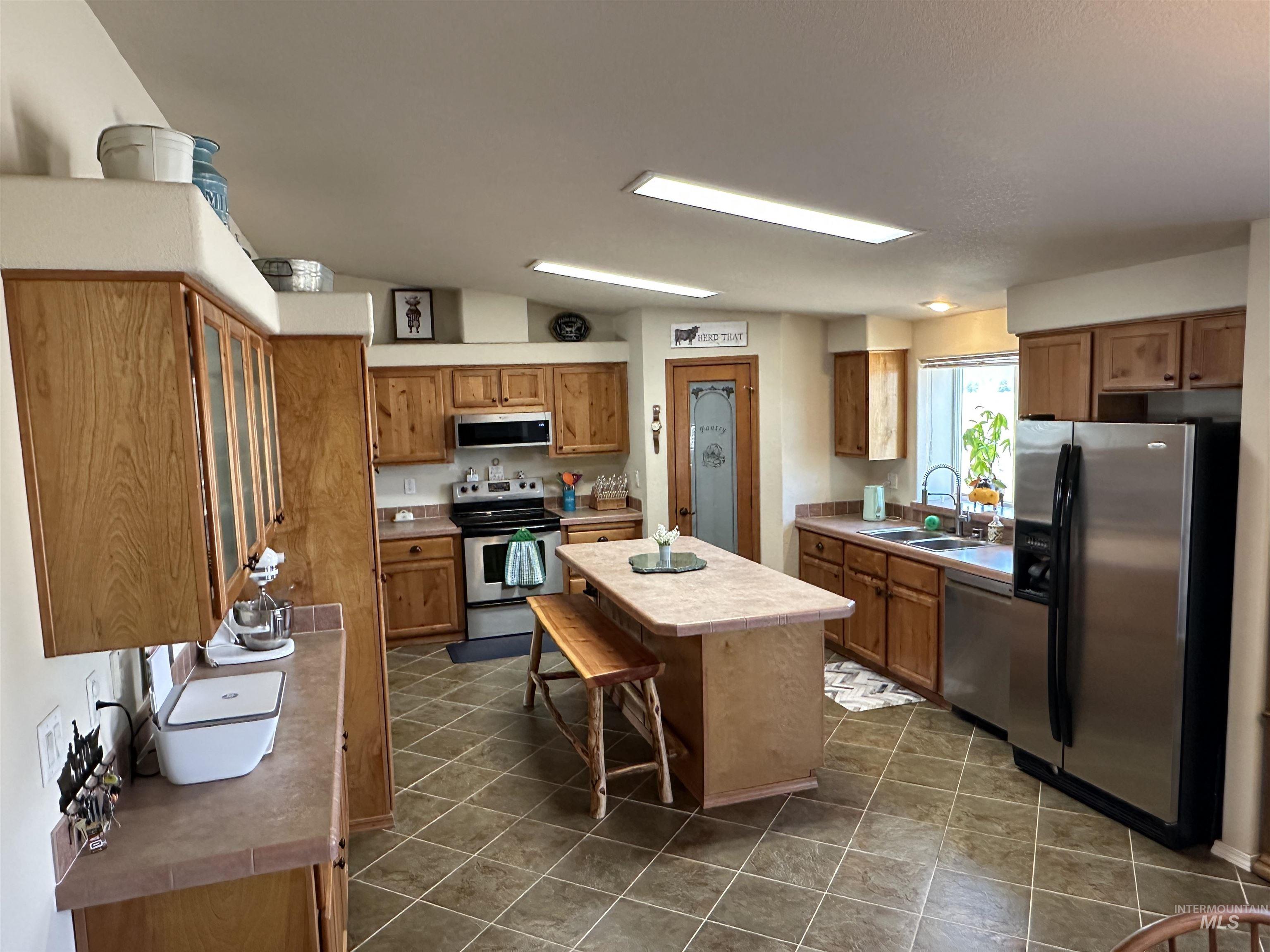 Kitchen featuring stainless steel appliances, brown cabinetry, a center island, and a breakfast bar area