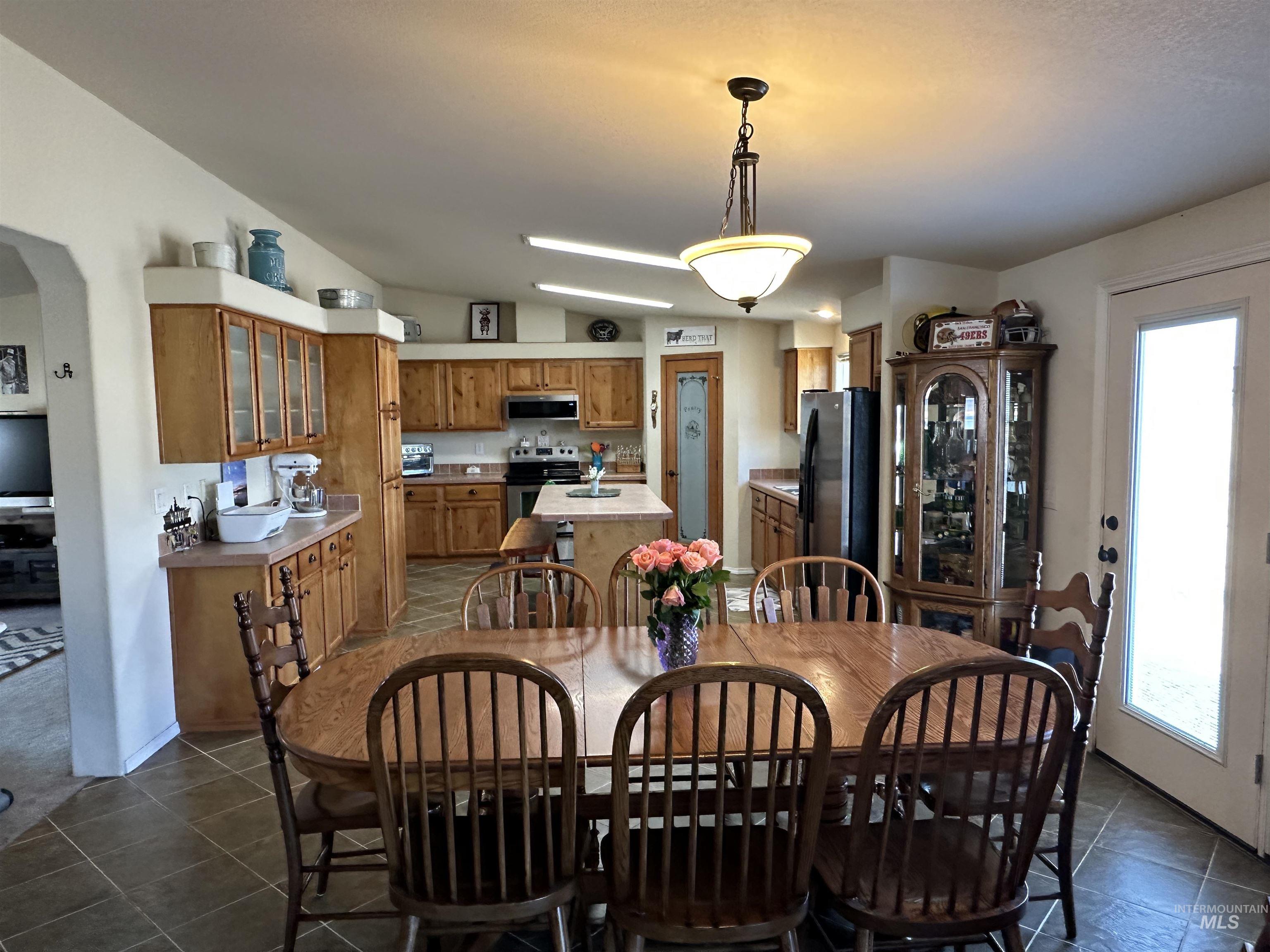 Dining area featuring arched walkways, dark tile patterned flooring, and lofted ceiling