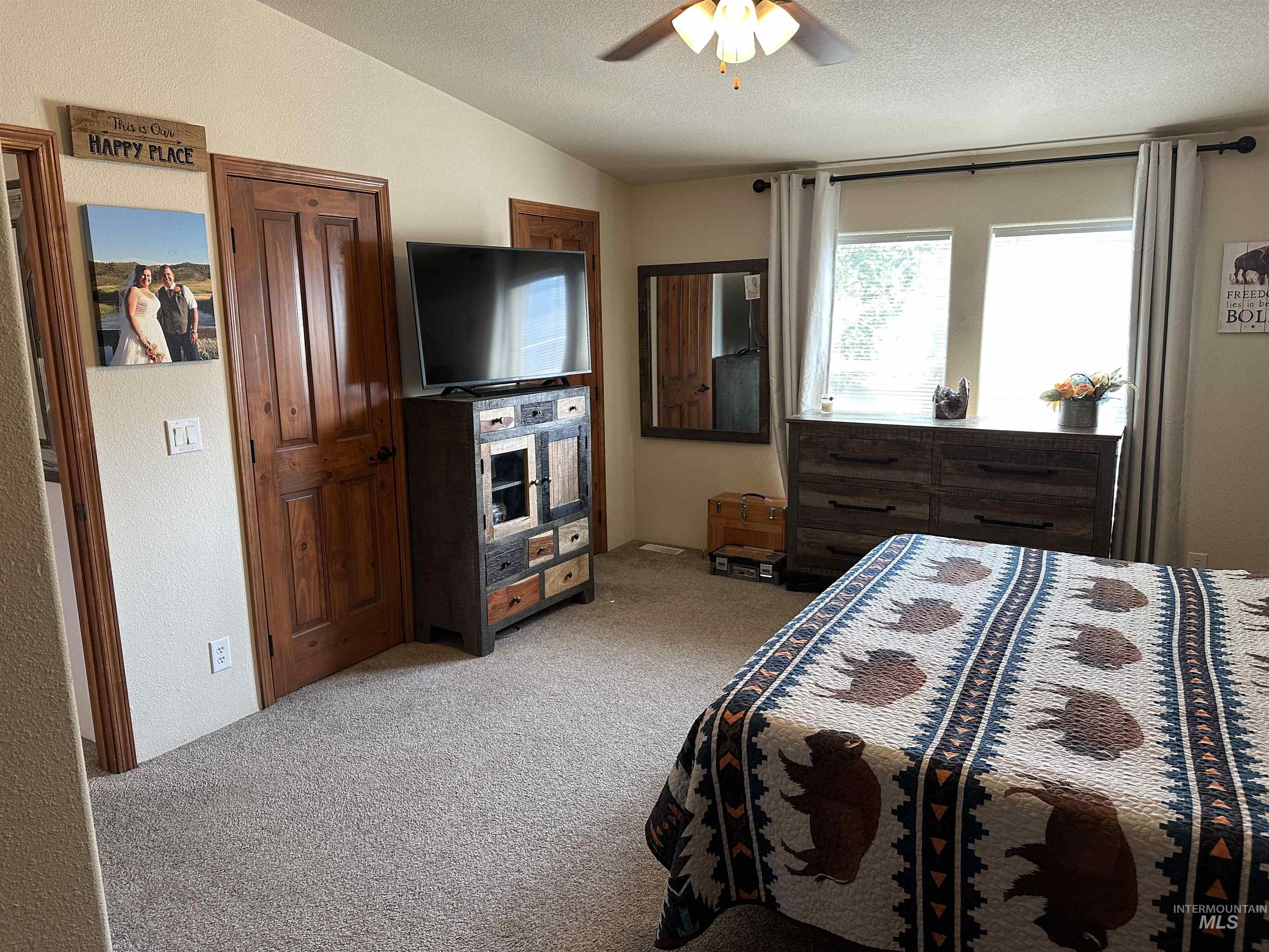 Bedroom with light carpet, ceiling fan, a textured ceiling, and vaulted ceiling