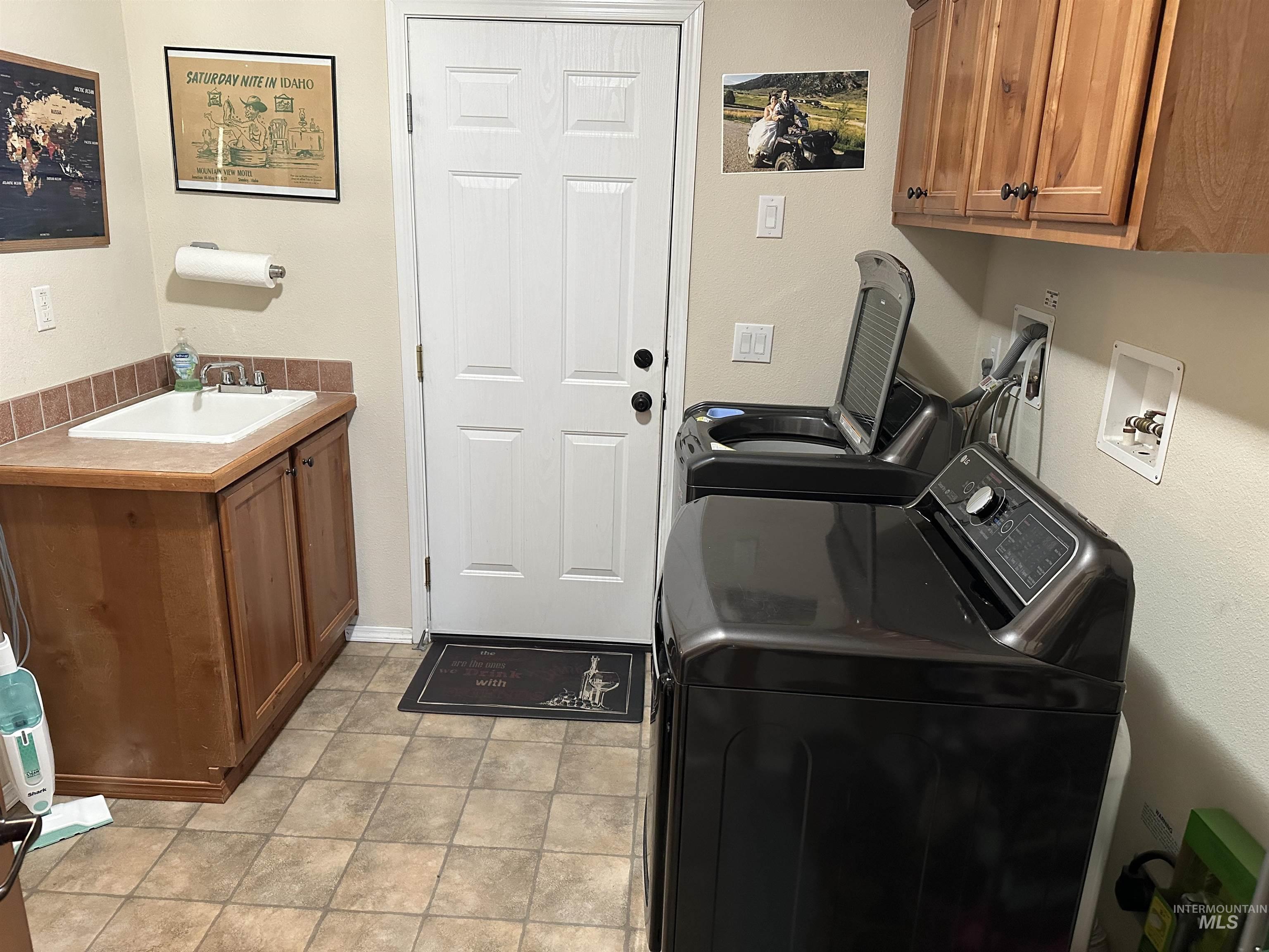 Washroom featuring cabinet space, independent washer and dryer, and light tile patterned floors