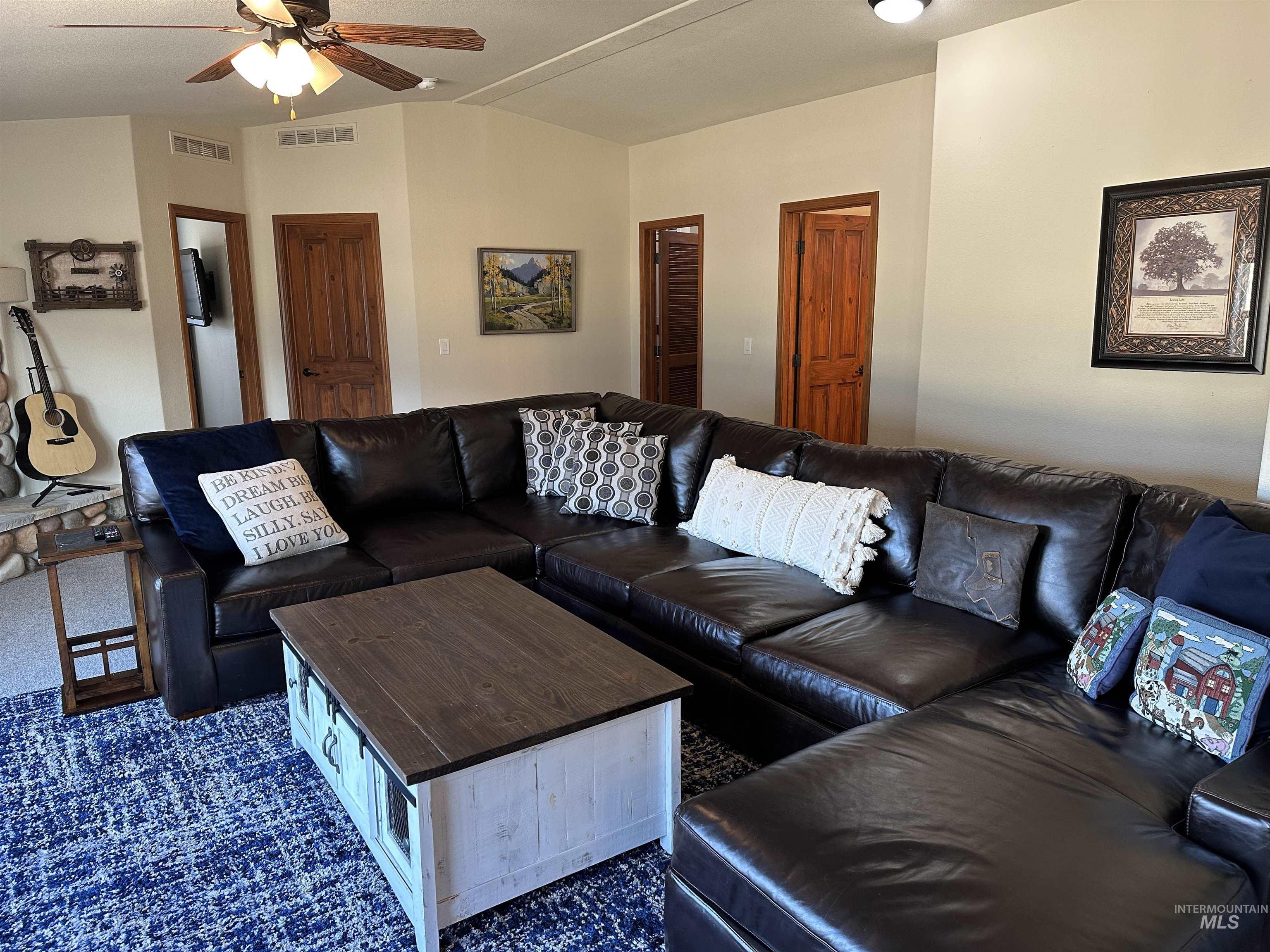 Living room with lofted ceiling, dark colored carpet, and a ceiling fan