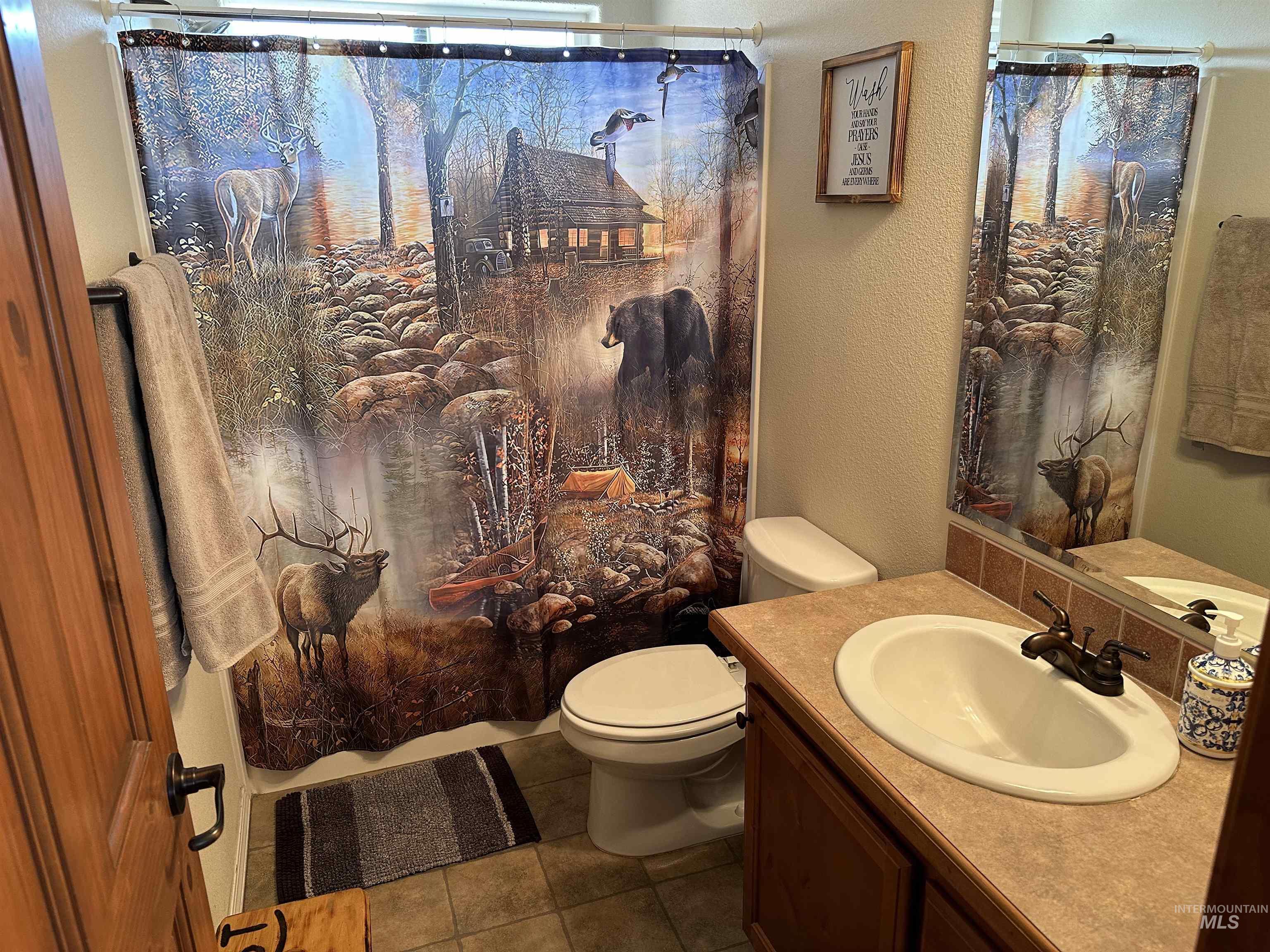 Bathroom with a textured wall, vanity, tile patterned flooring, and curtained shower