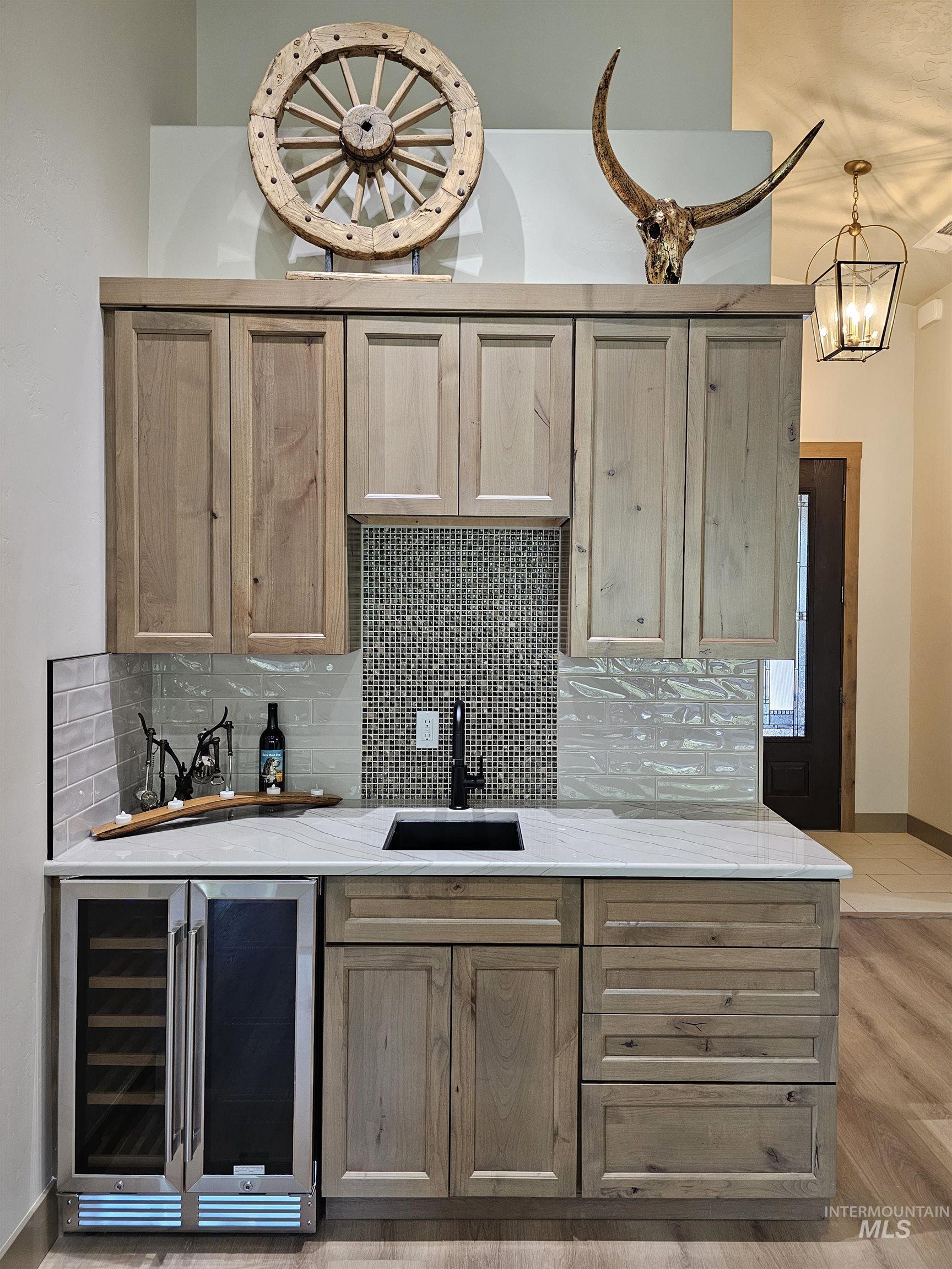 Bar area featuring beverage cooler, sink and alder cabinets for extra storage.