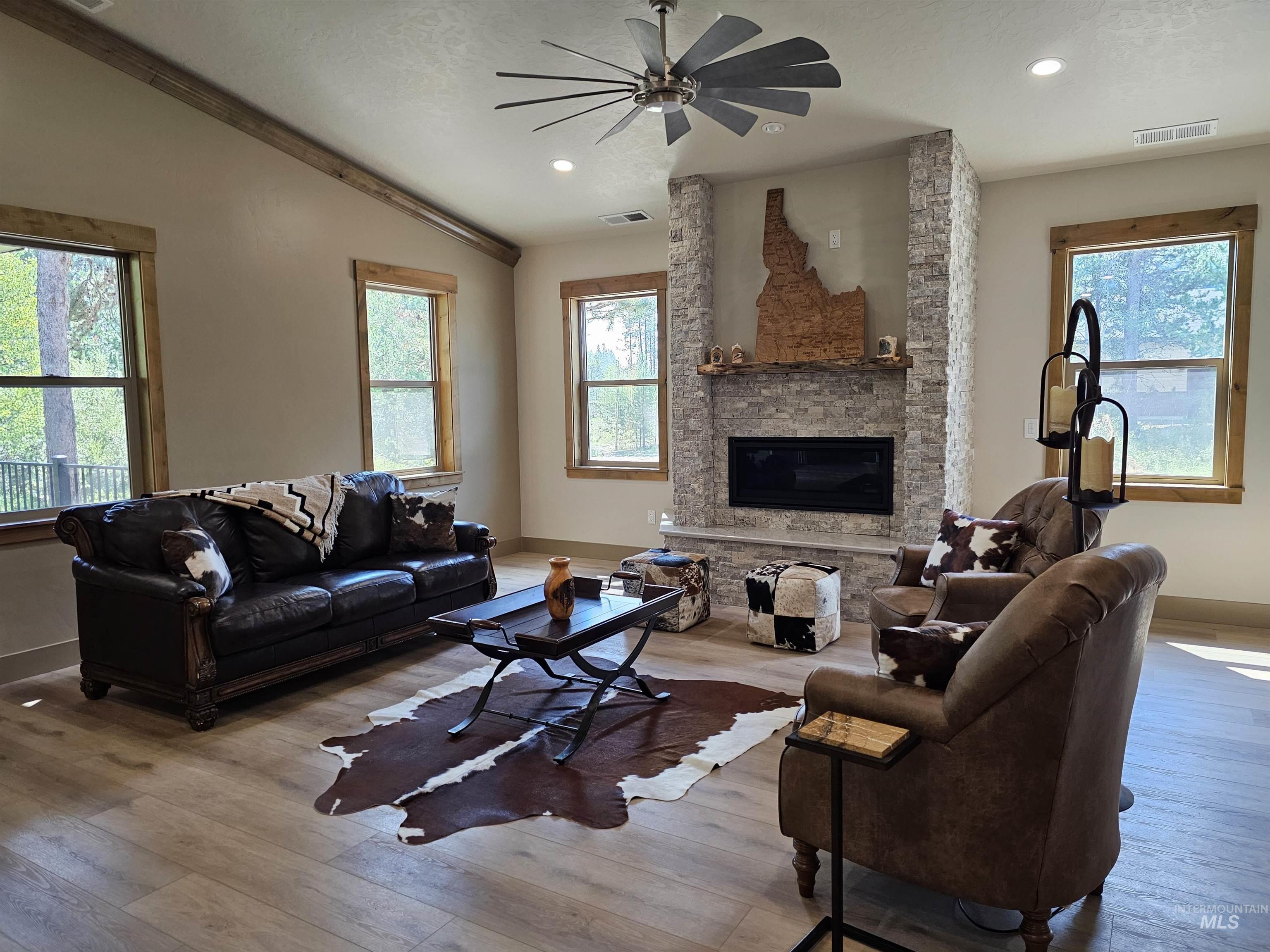 Living room featuring vinyl plank floors, propane fireplace, ceiling fan and recessed lighting.