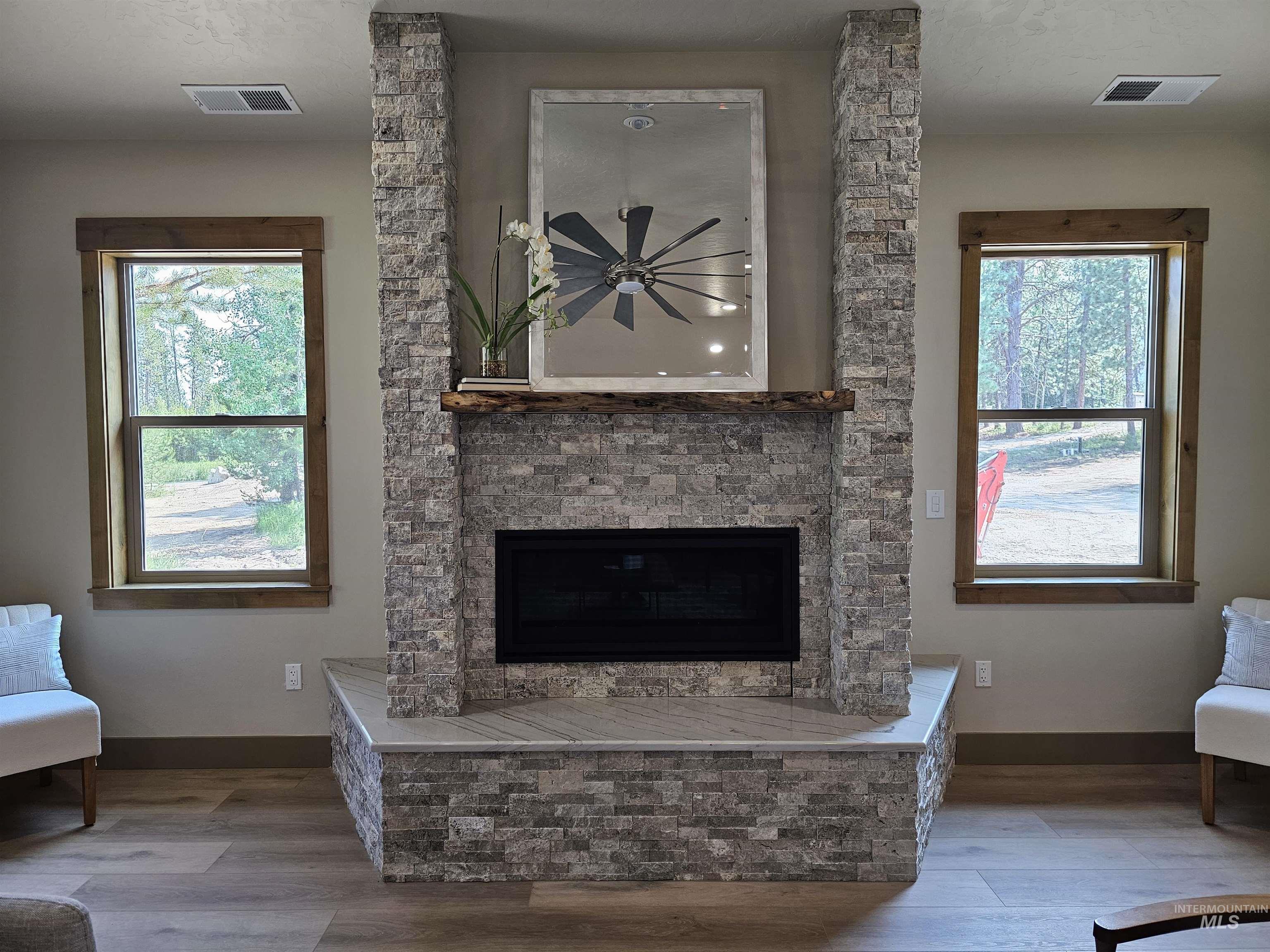Propane fireplace has a stone surround, granite hearth and live edge pine slab mantel.