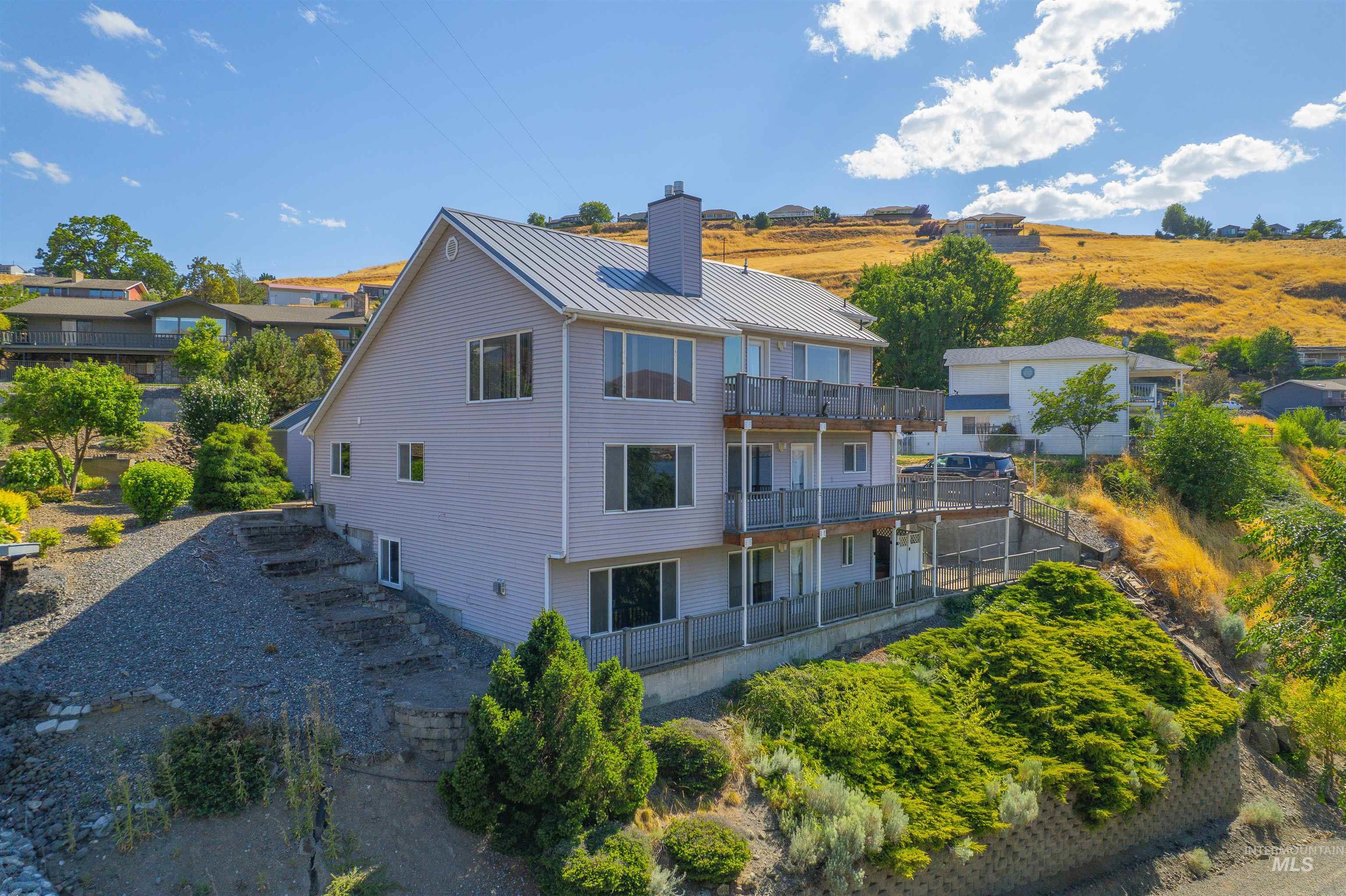 Back of property featuring a balcony, a chimney, and a metal roof