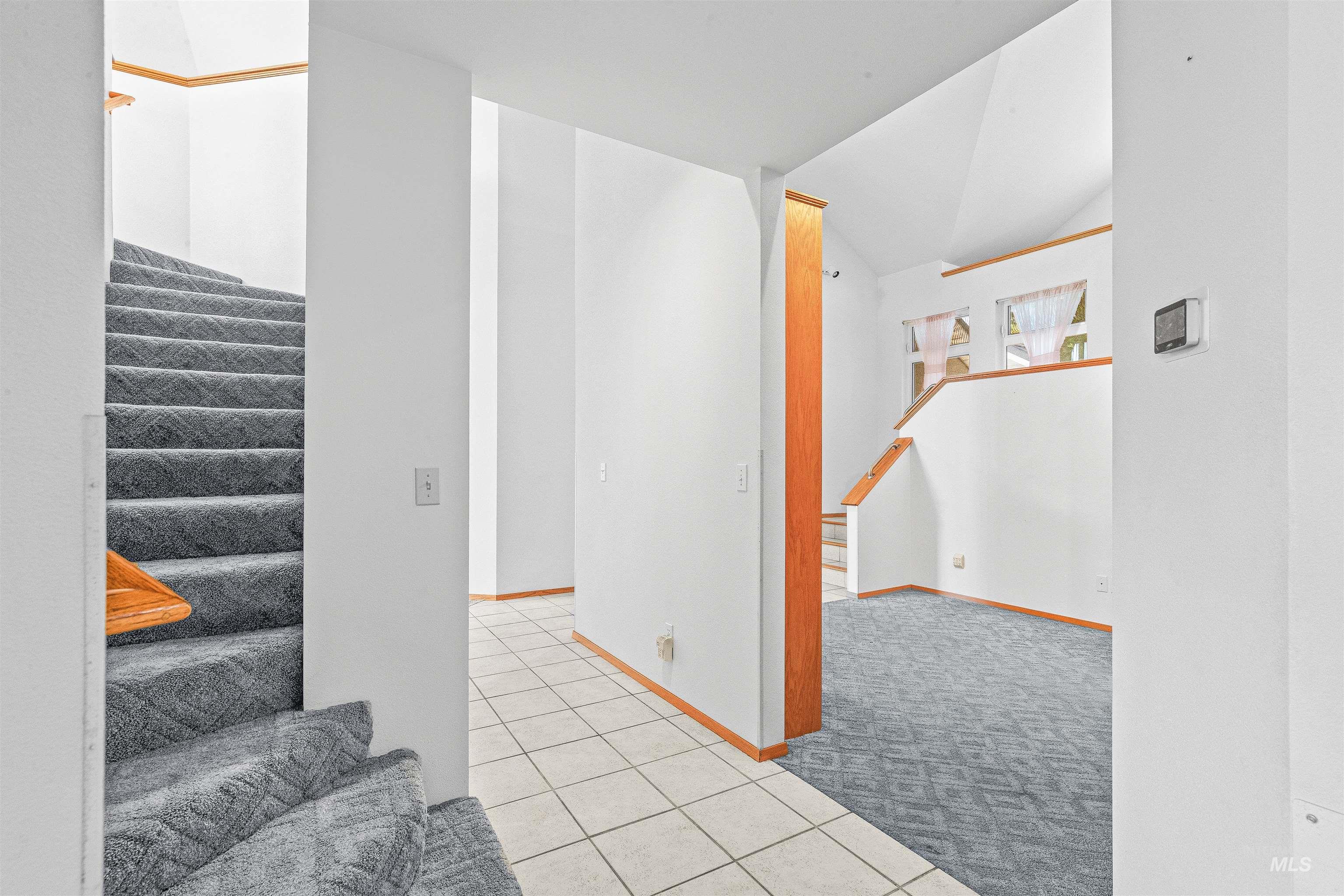 Stairway with tile patterned flooring, carpet flooring, and vaulted ceiling