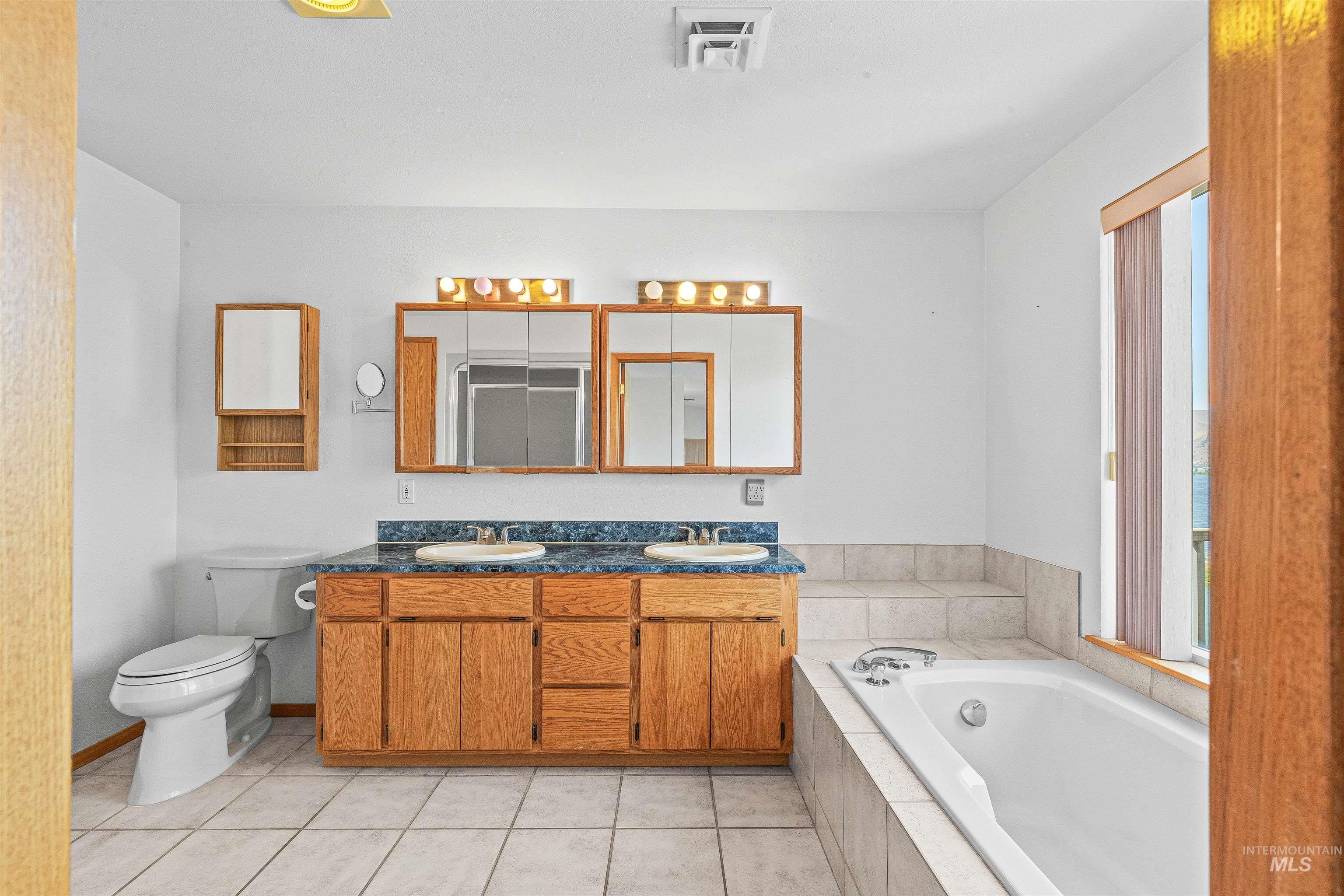 Full bath with a bath, double vanity, plenty of natural light, and tile patterned floors
