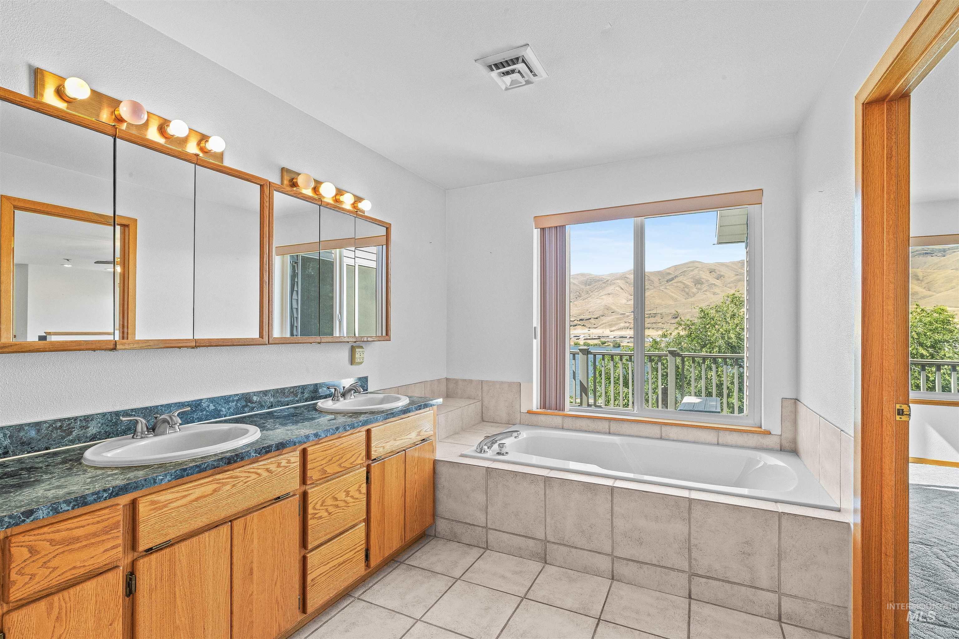 Full bathroom featuring a mountain view, double vanity, a garden tub, and tile patterned flooring