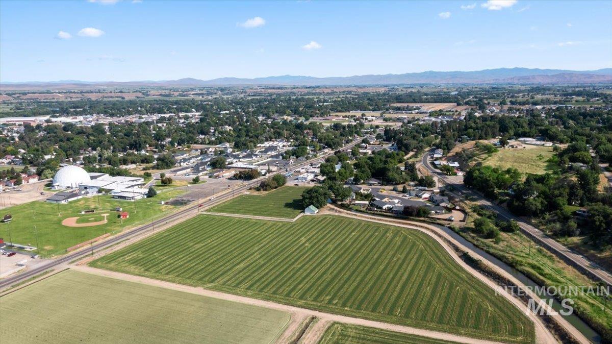 Aerial view of property and surrounding area featuring a mountainous background and rural landscape