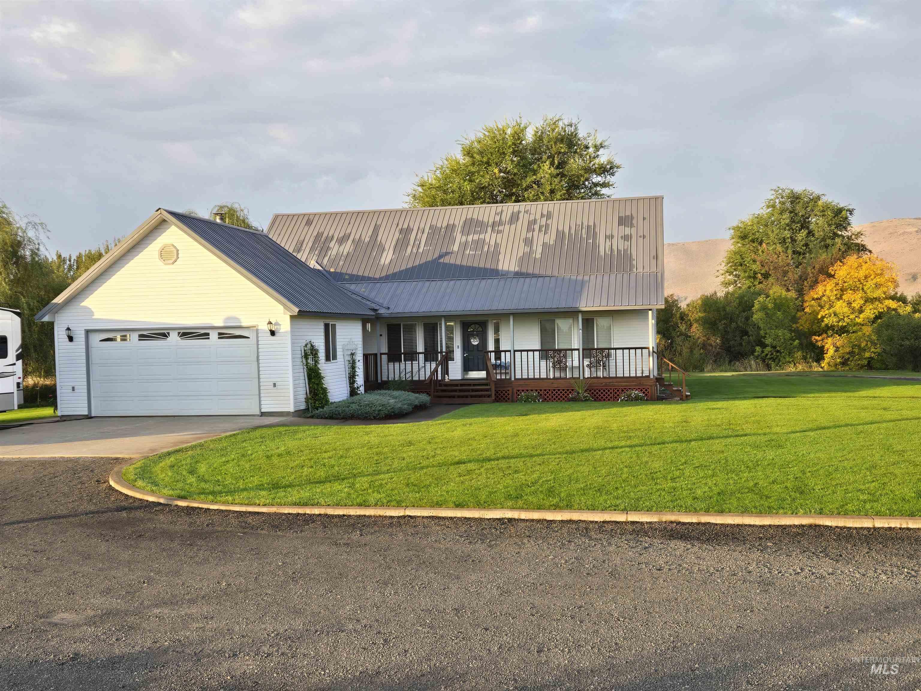 View of front of home with a porch, a front yard, driveway, and an attached garage