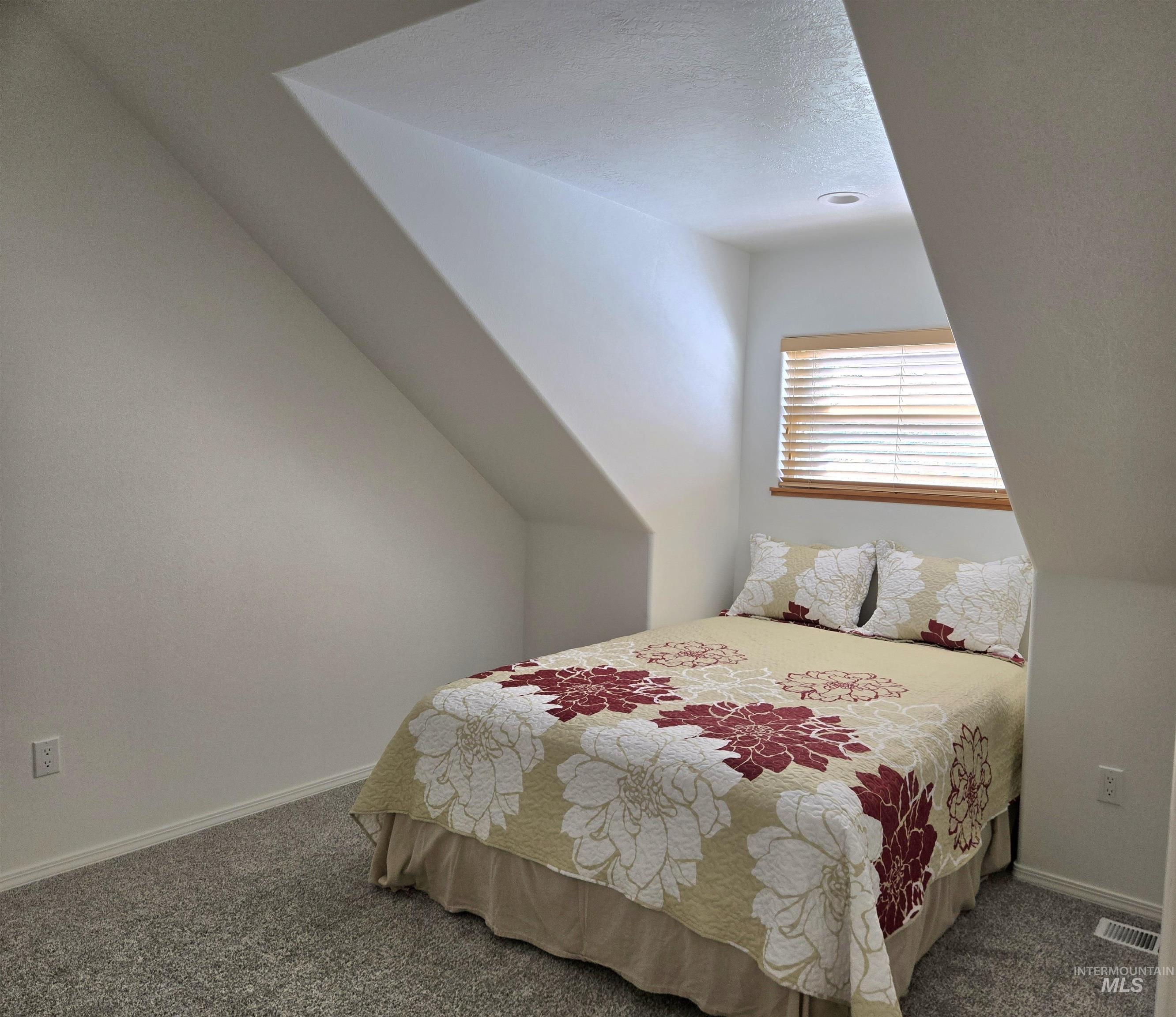 Bedroom with a textured ceiling and carpet flooring