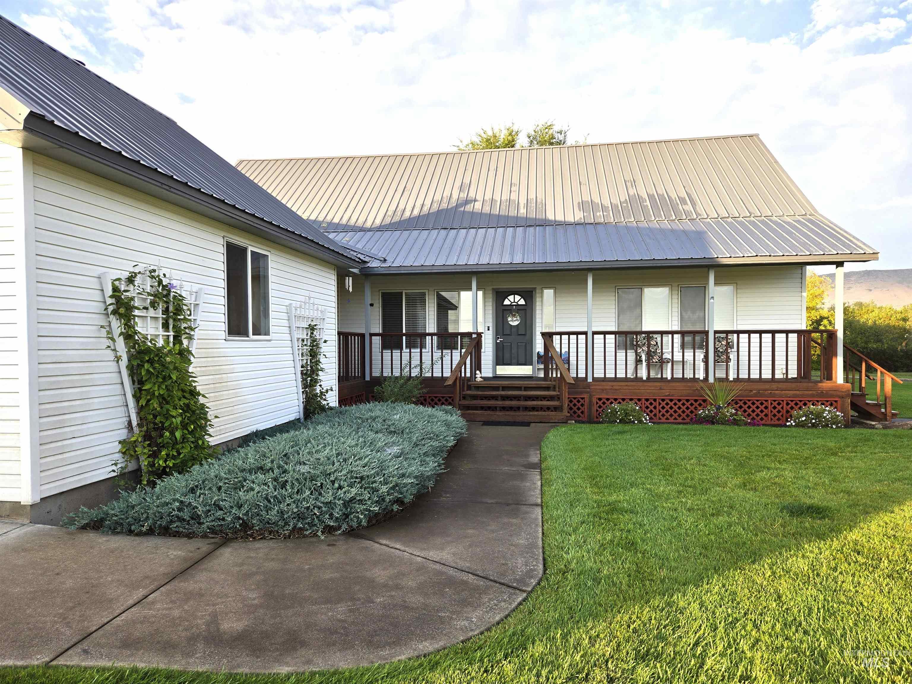 View of front facade with a metal roof, a porch, and a front lawn