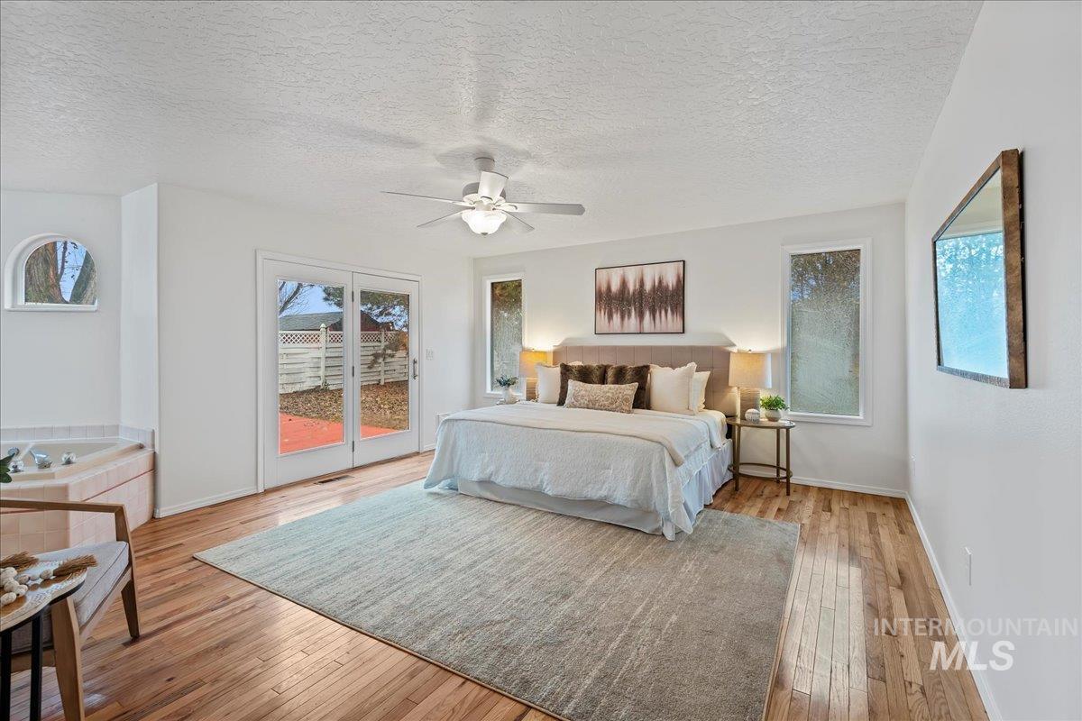 Bedroom with access to outside, light wood-style flooring, a textured ceiling, and ceiling fan