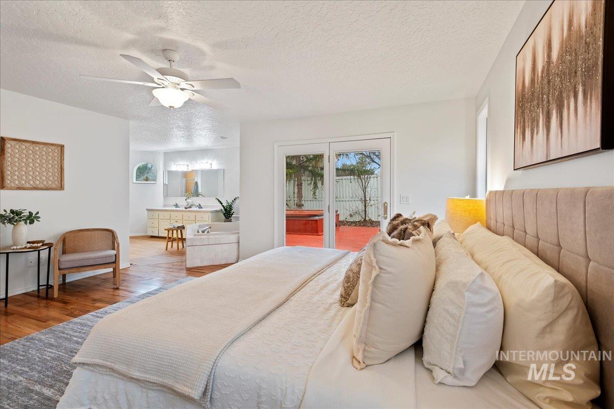 Bedroom featuring access to outside, a textured ceiling, wood finished floors, and ceiling fan