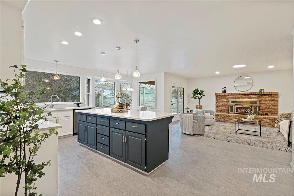 Kitchen featuring hanging light fixtures, a brick fireplace, recessed lighting, white cabinets, and light stone countertops