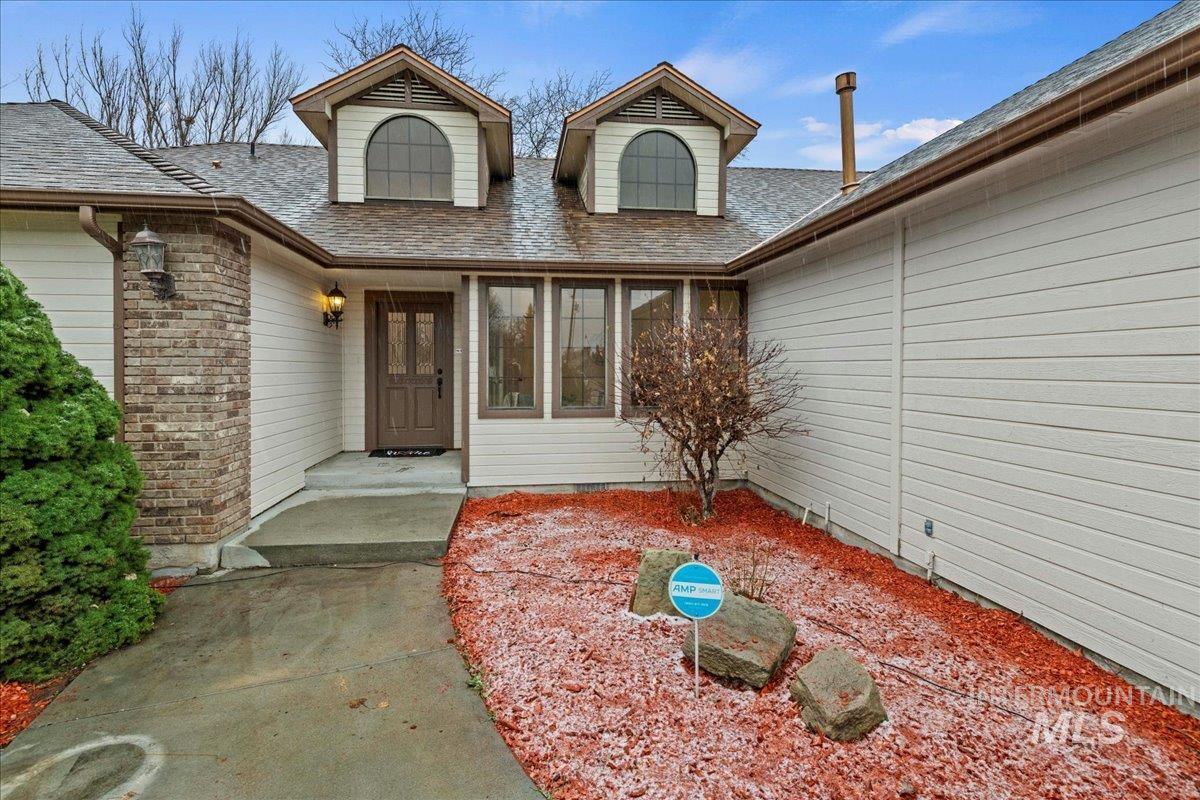 Property entrance featuring roof with shingles and brick siding