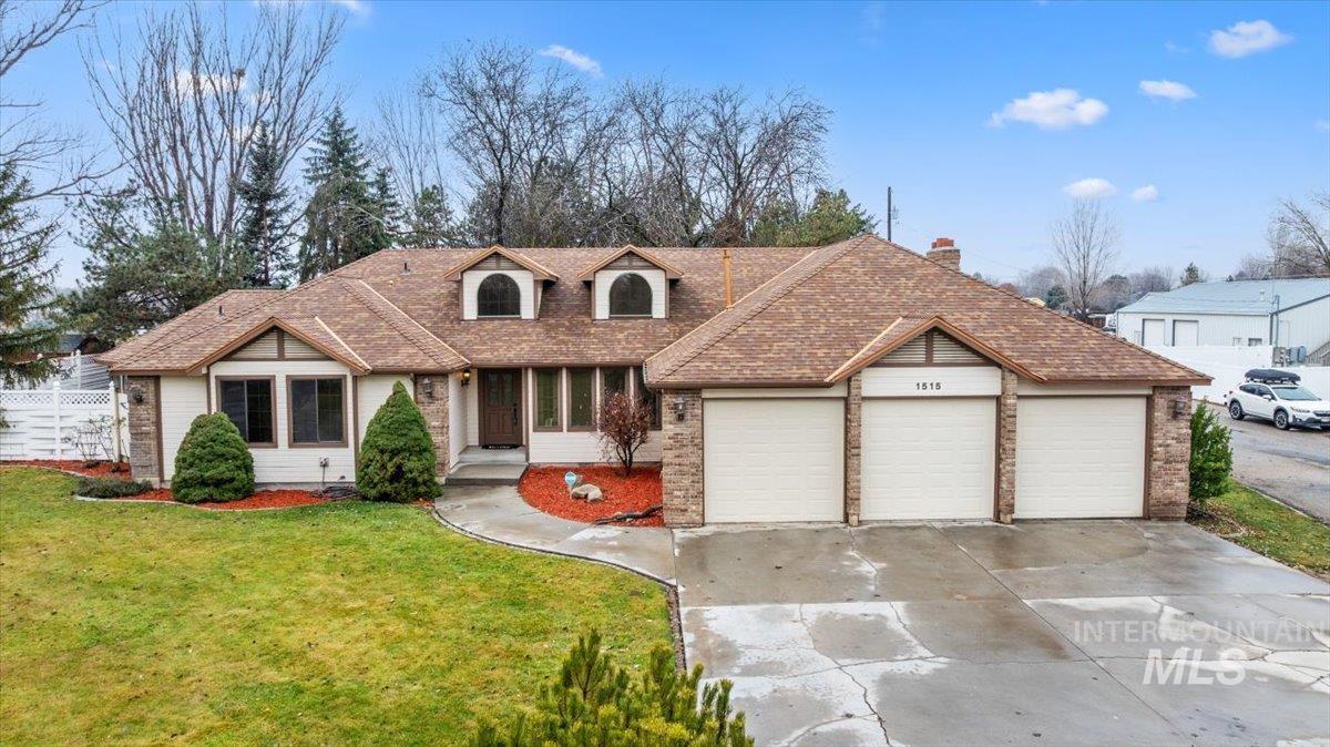 View of front of house featuring a front yard, a garage, driveway, and brick siding