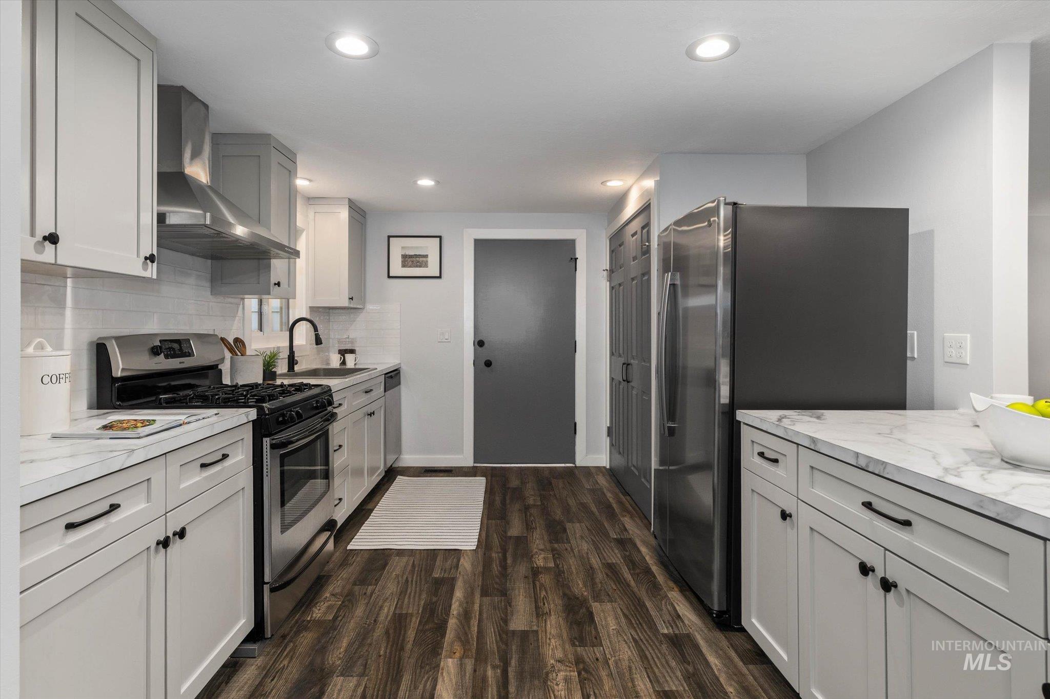 Kitchen featuring stainless steel appliances, light countertops, dark wood-type flooring, recessed lighting, and decorative backsplash