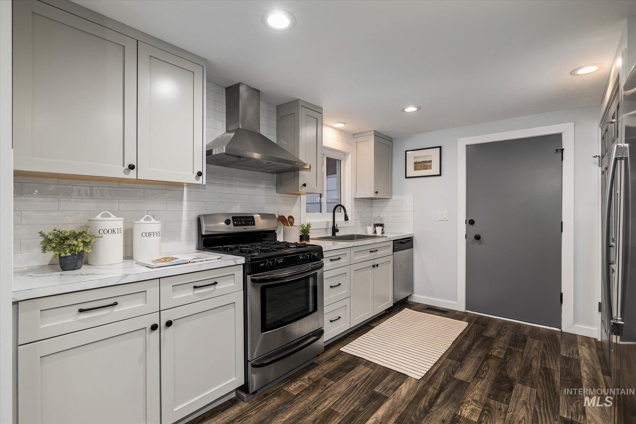 Kitchen featuring stainless steel appliances, light countertops, dark wood finished floors, recessed lighting, and decorative backsplash