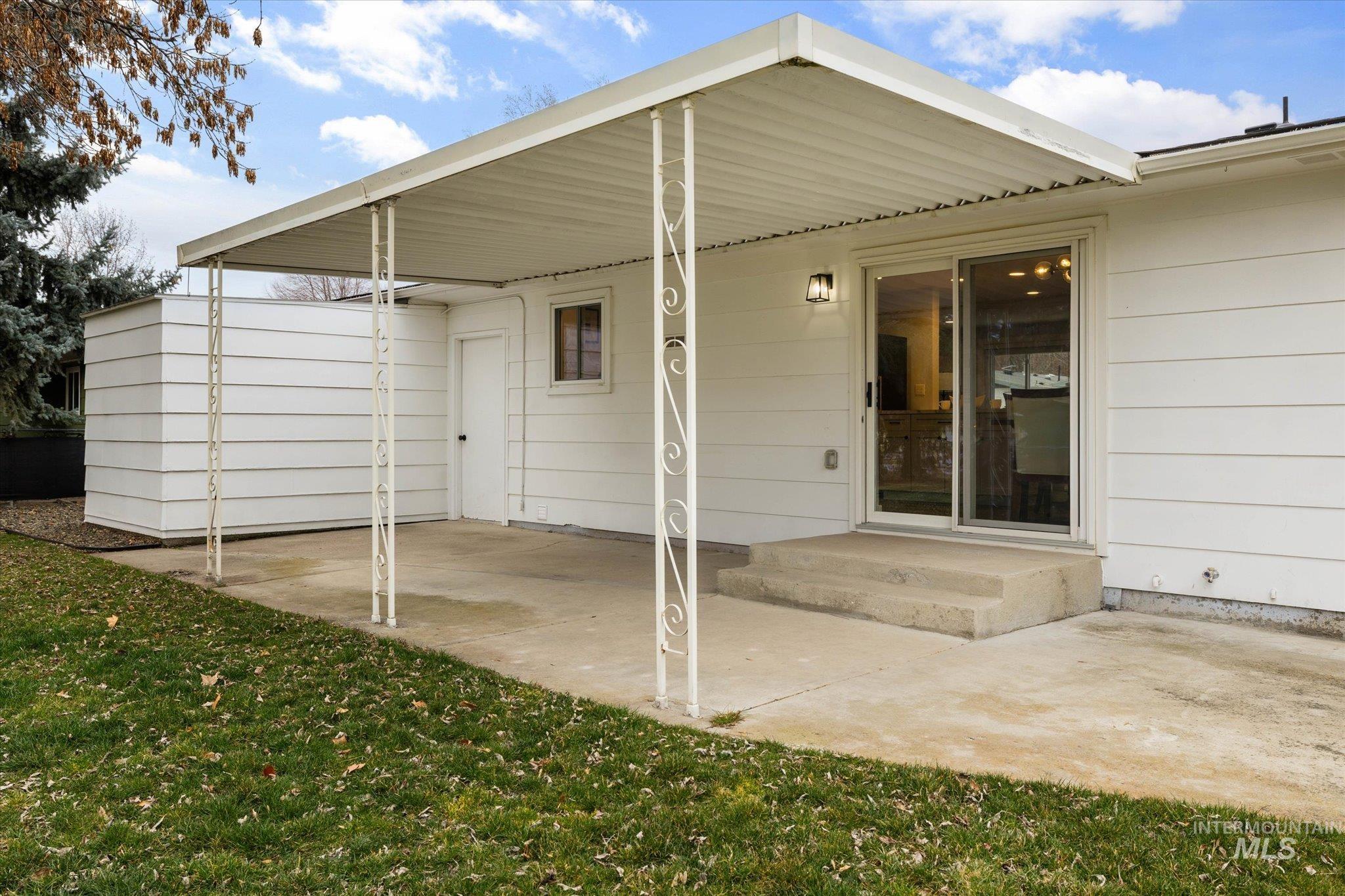 Rear view of property with a lawn and a patio