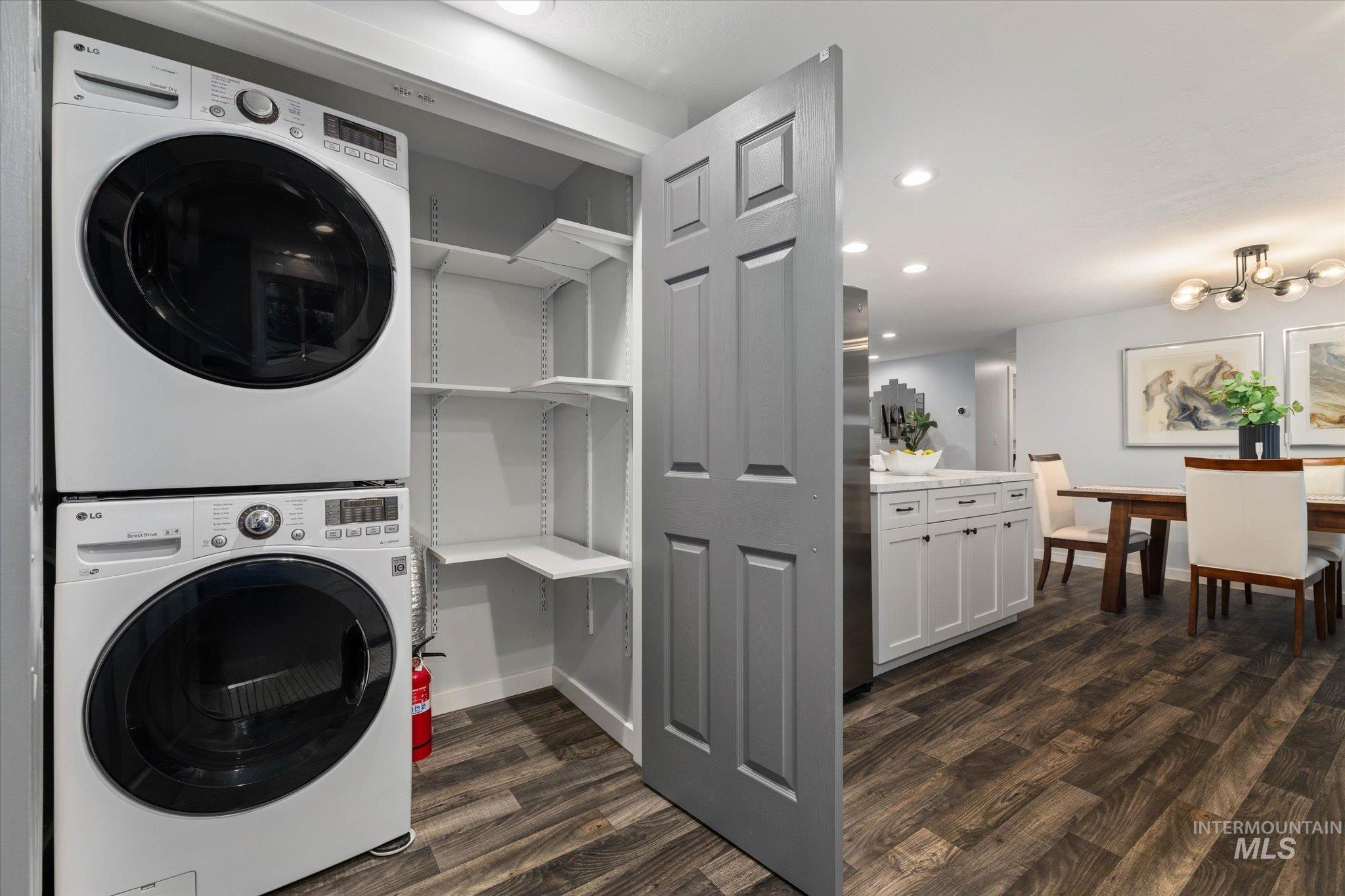 Laundry area featuring dark wood finished floors, recessed lighting, and stacked washer / dryer