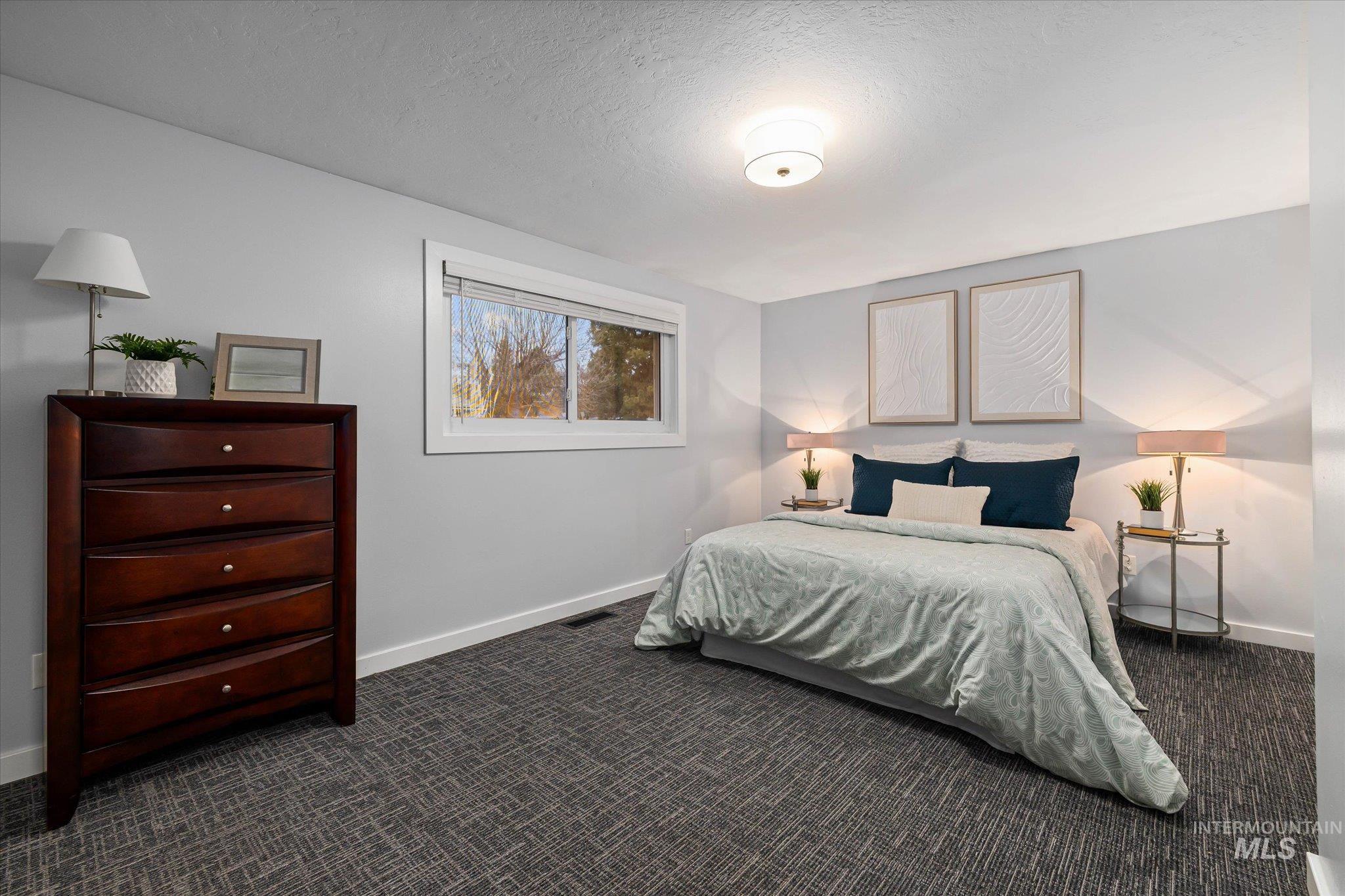 Bedroom featuring dark colored carpet and a textured ceiling