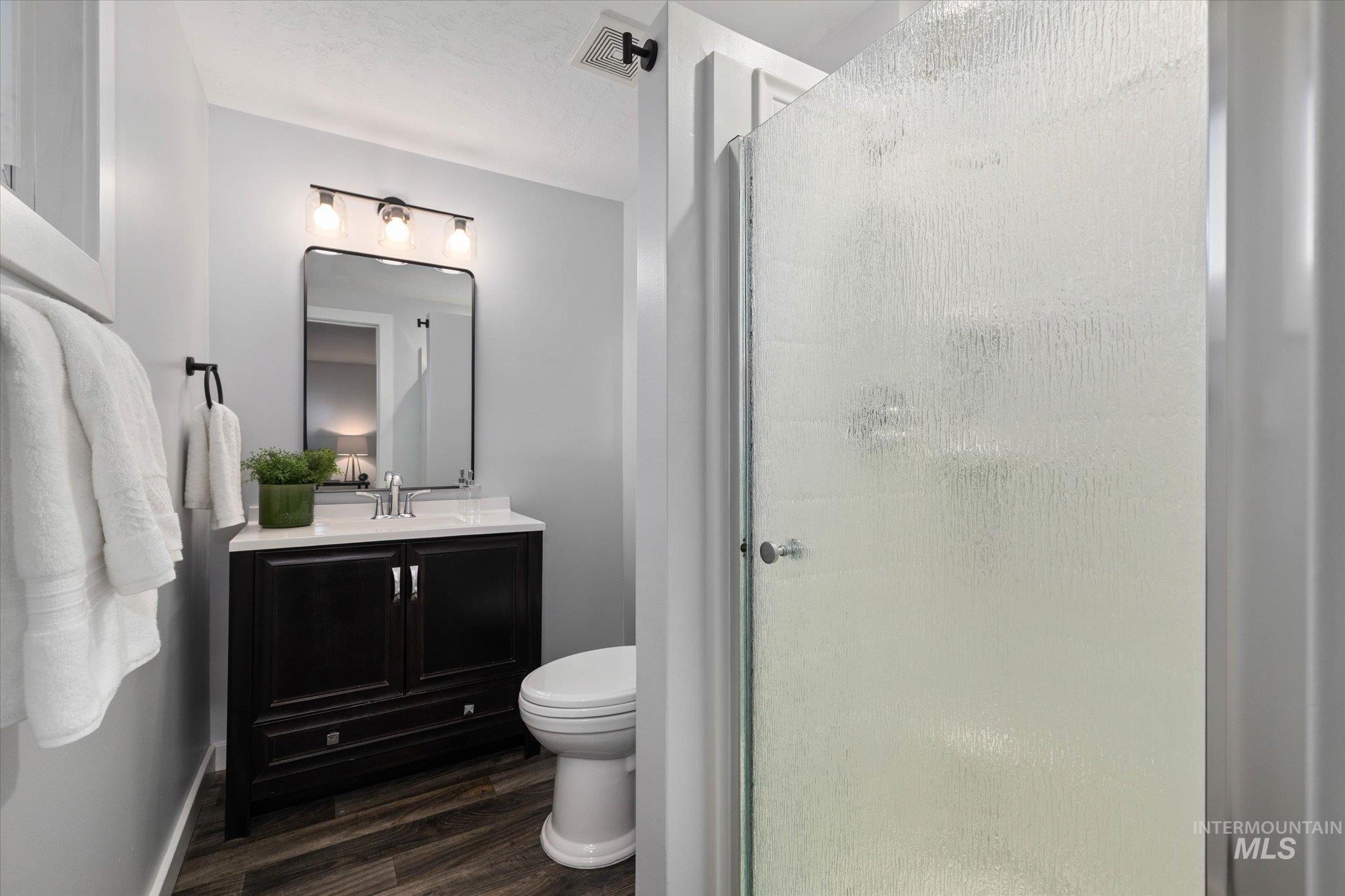 Bathroom featuring vanity, a stall shower, and dark wood-type flooring