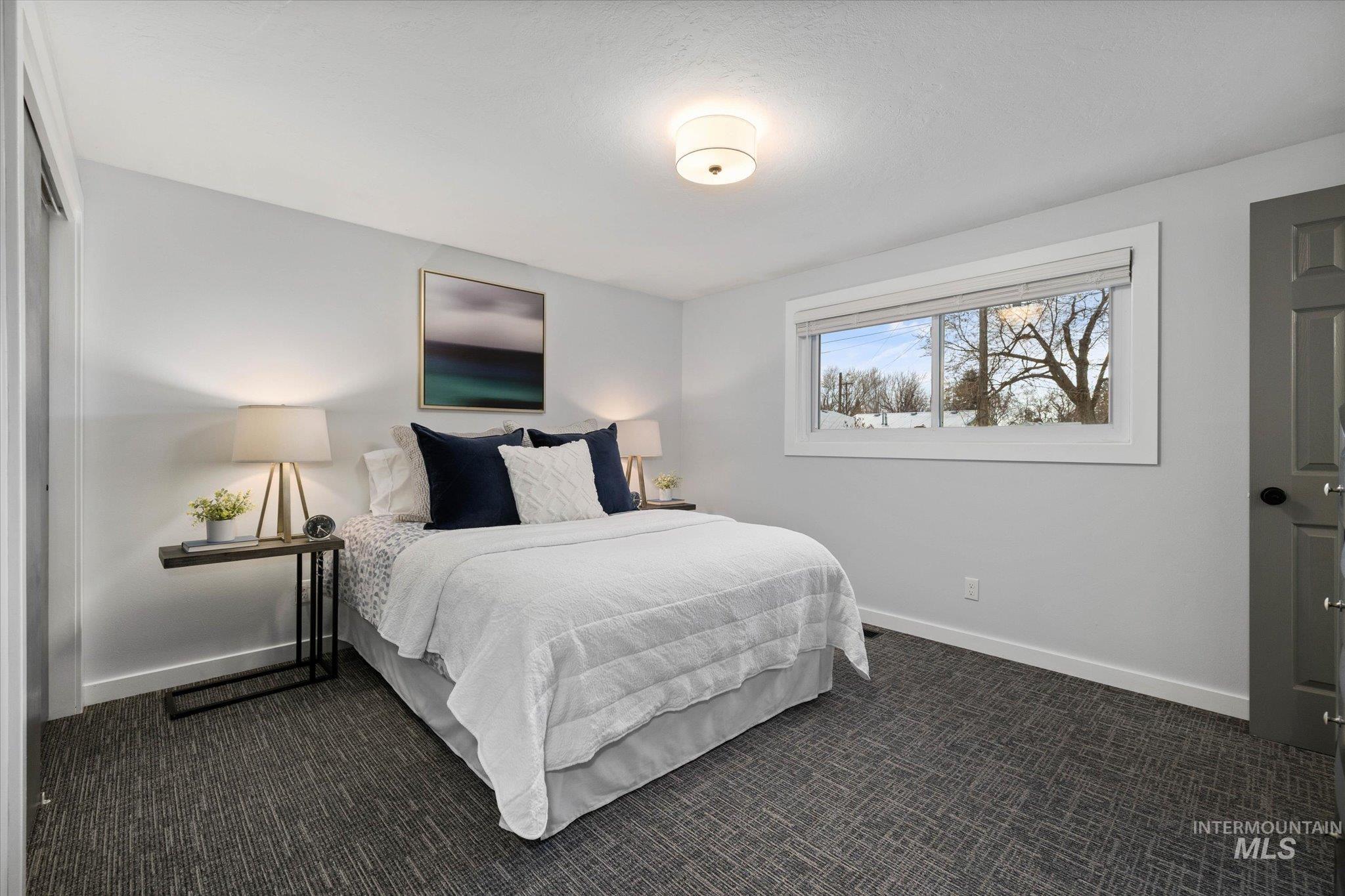 Bedroom with dark carpet and baseboards