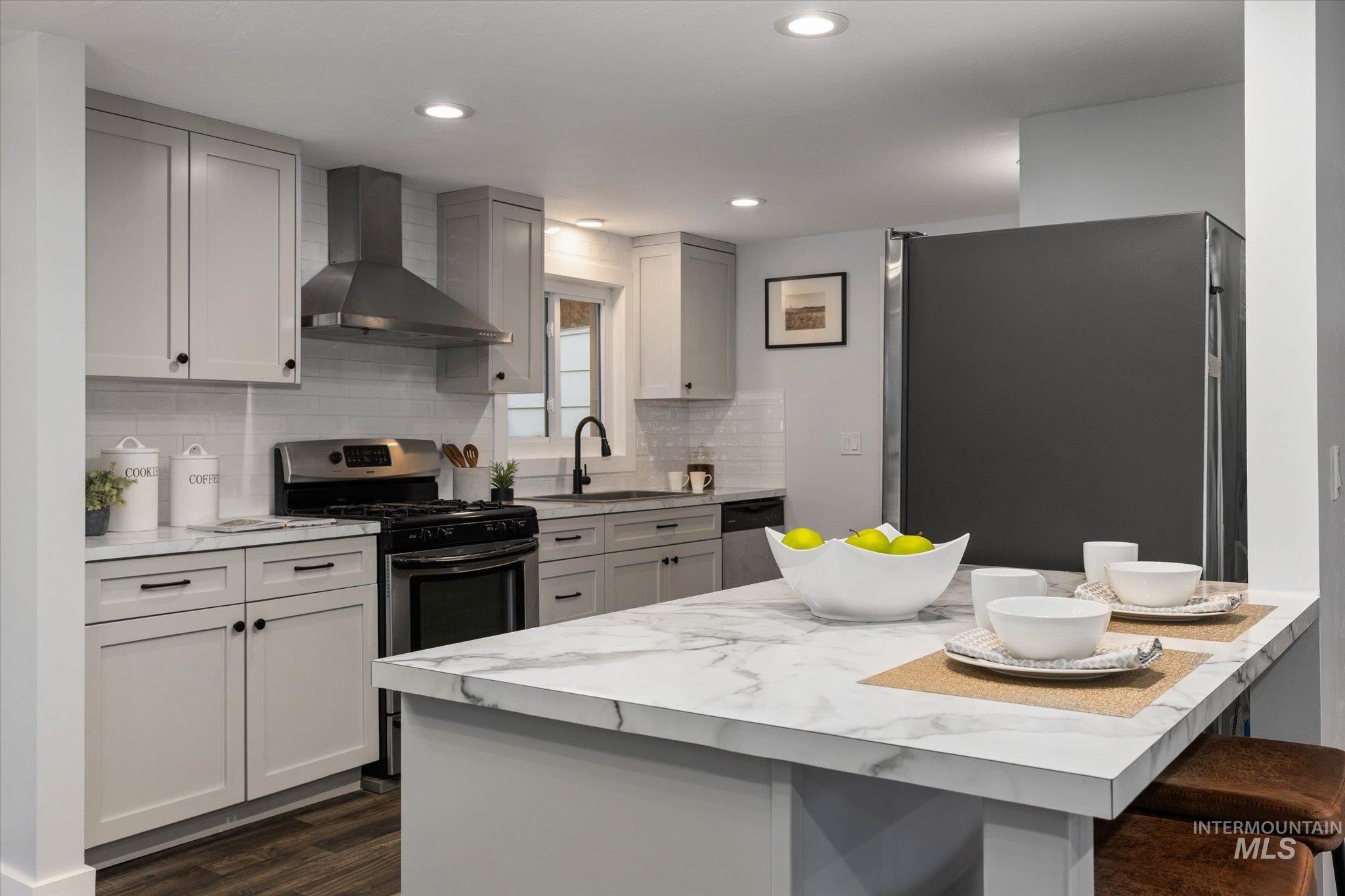 Kitchen featuring stainless steel appliances, a kitchen breakfast bar, dark wood-style floors, gray cabinetry, and recessed lighting