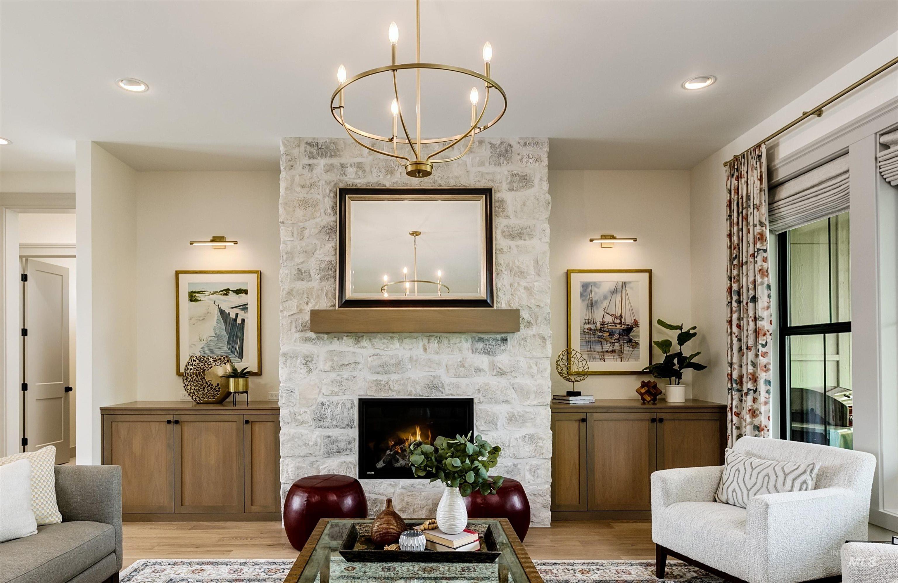 Great room featuring a full-height stone fireplace with a wood mantel, an ornate chandelier, recessed lighting, and built-in wood-finish cabinetry