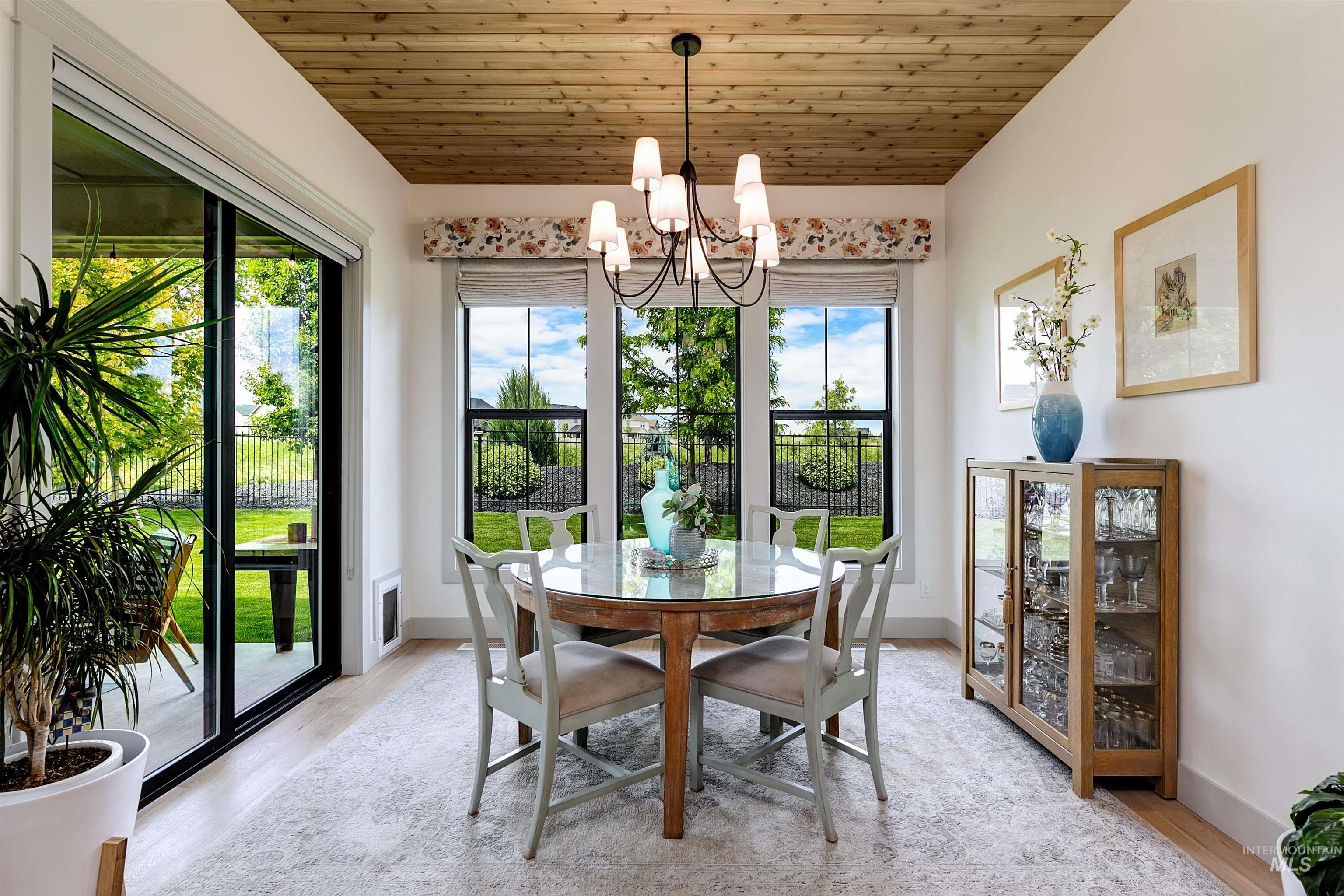 Dining area featuring a wood-paneled ceiling, large glass sliding doors, and multiple windows