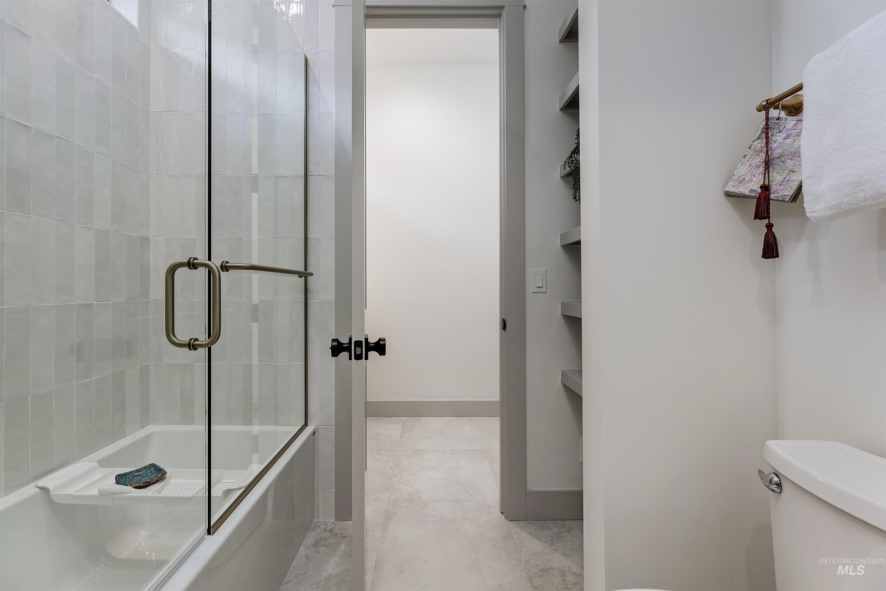 Bathtub and shower combination featuring a clear glass enclosure and light-toned tile surround