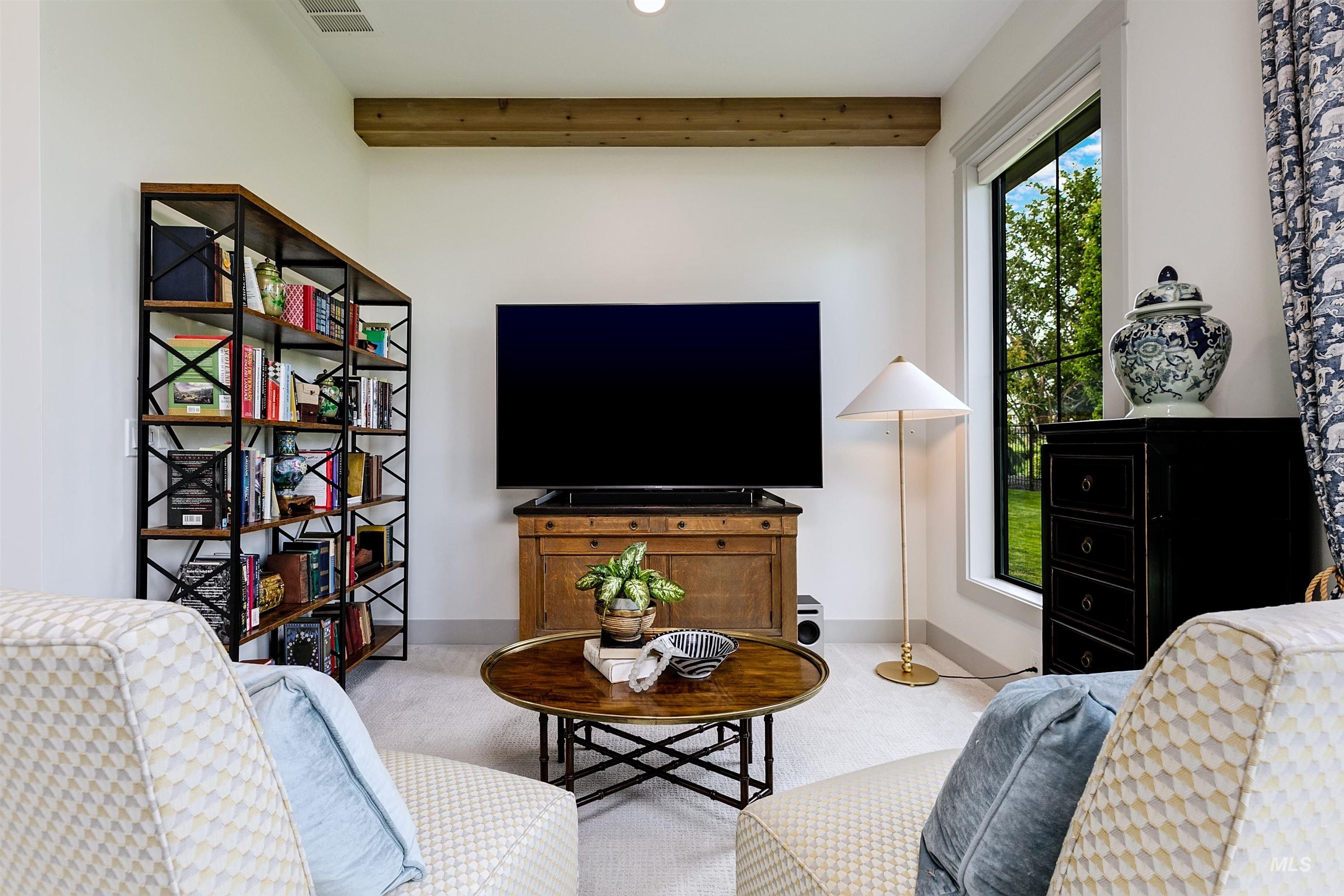 Carpeted interior space featuring a large picture window, a rustic wood beam, and a built-in entertainment console